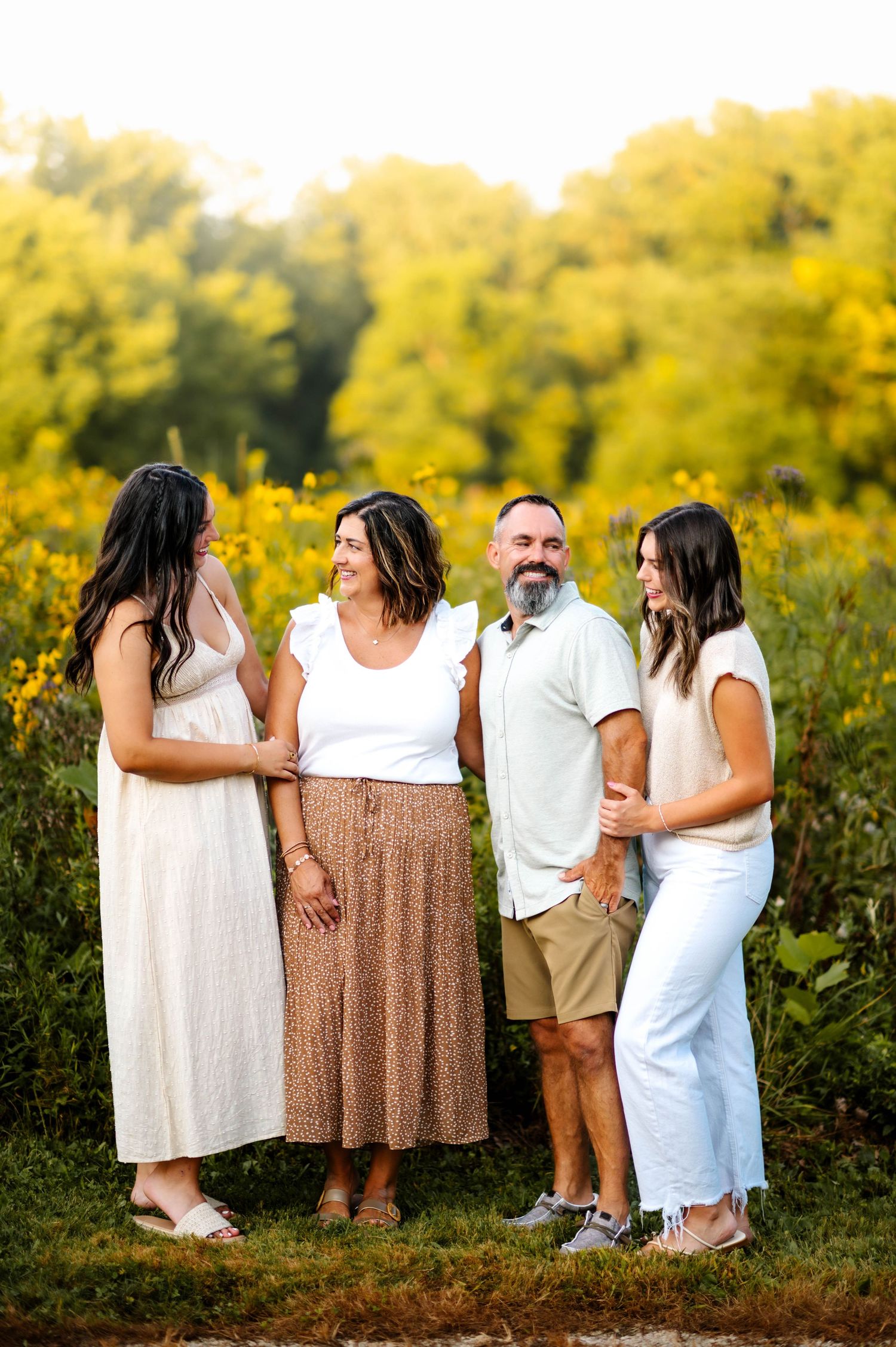 Group photo of family members embracing in a field of yellow summer flowers.