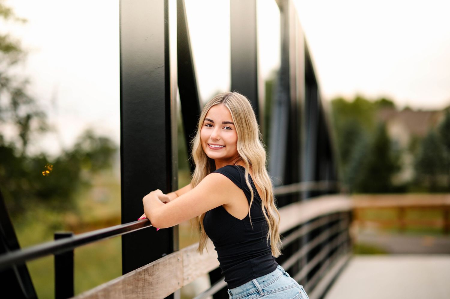Casual outdoor portrait session on a metal bridge with natural lighting at sunset.