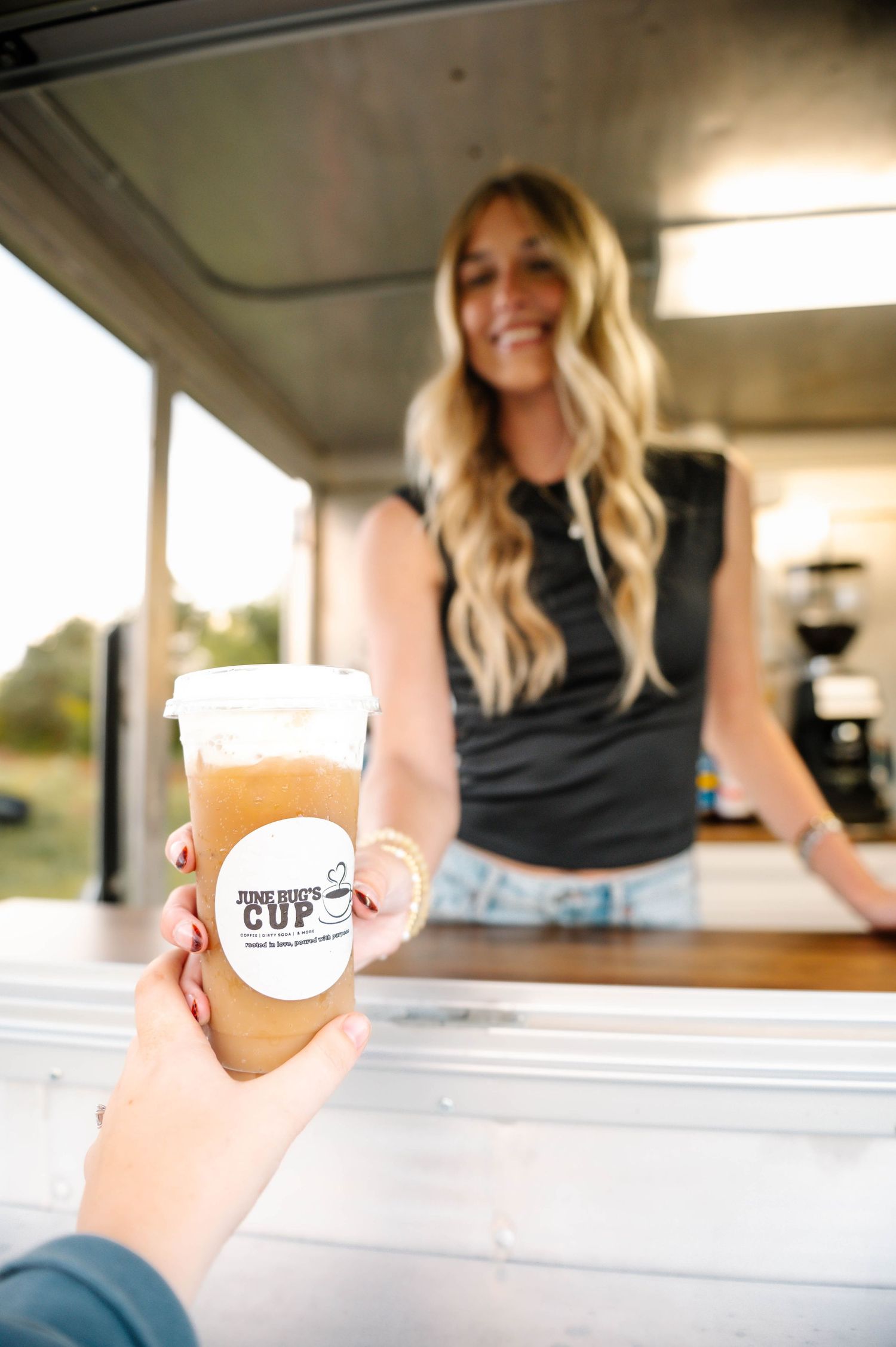 Customer receiving drink orders through coffee truck service window.