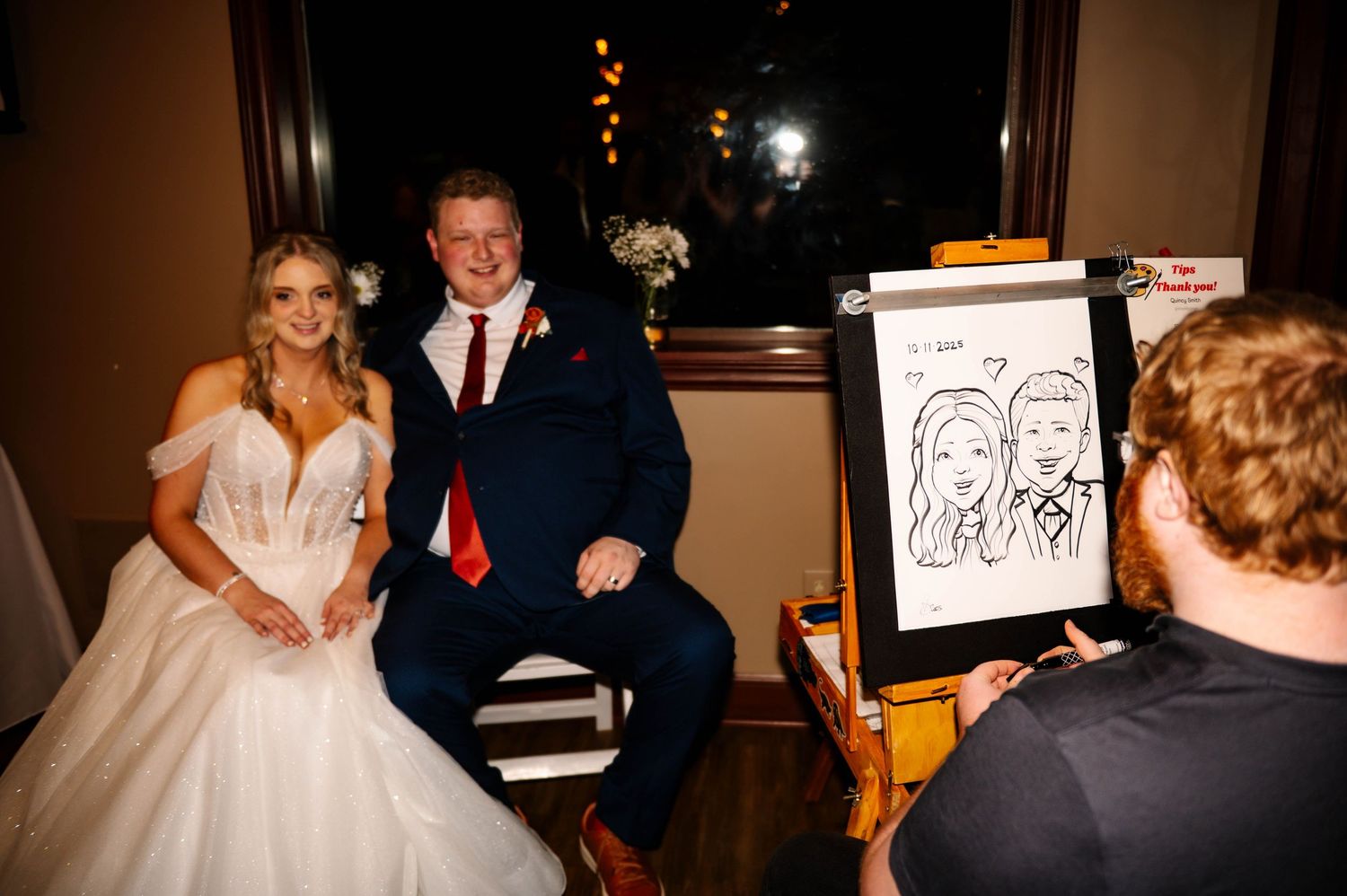 Wedding reception venue with string lights and artistic caricature drawings on display.