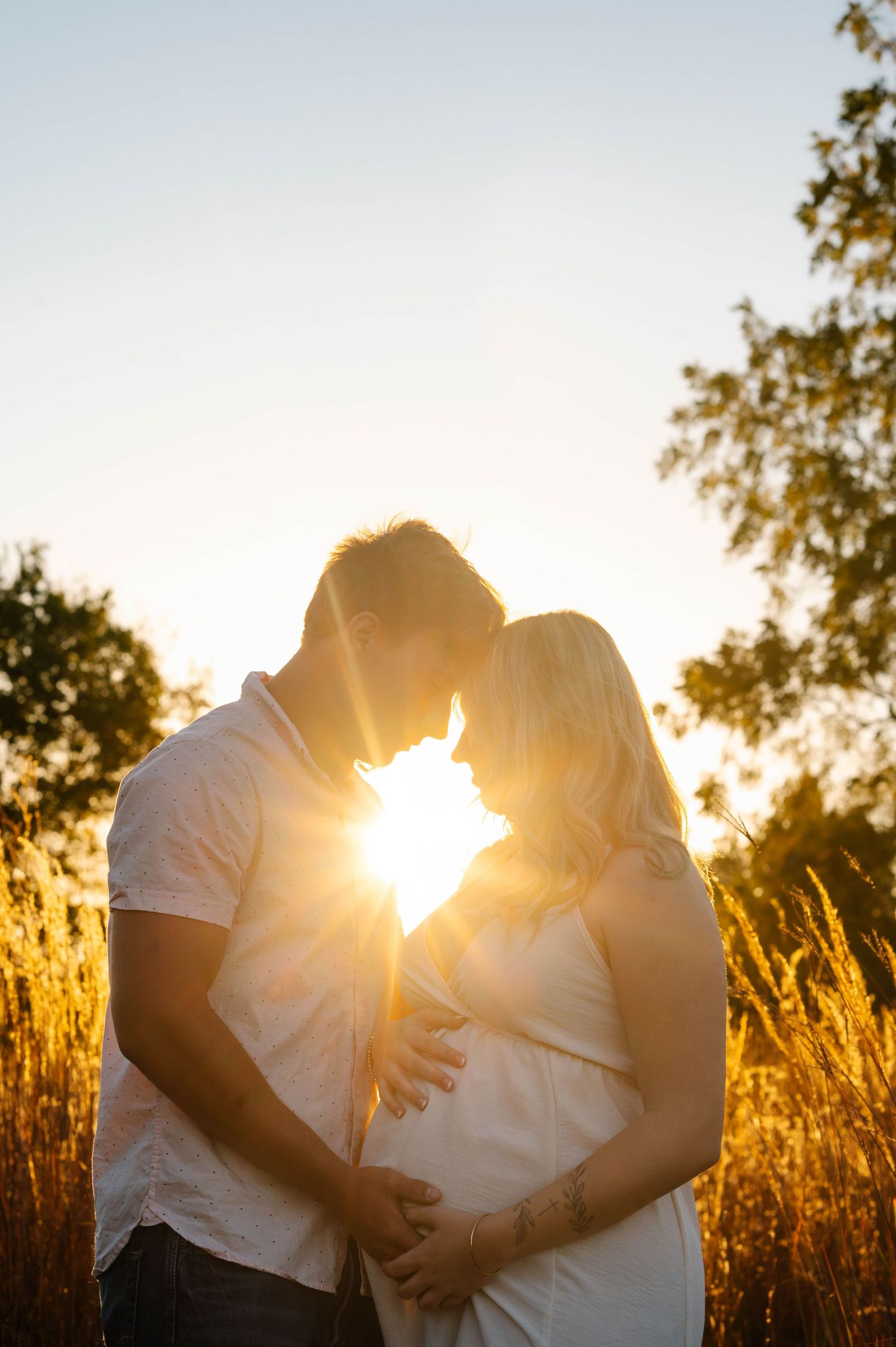 Silhouetted couple sharing tender moment in golden sunset field.