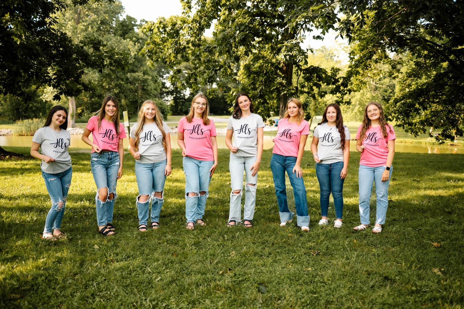 Group photo showing people arranged in a line wearing coordinated outfits on a grassy lawn.