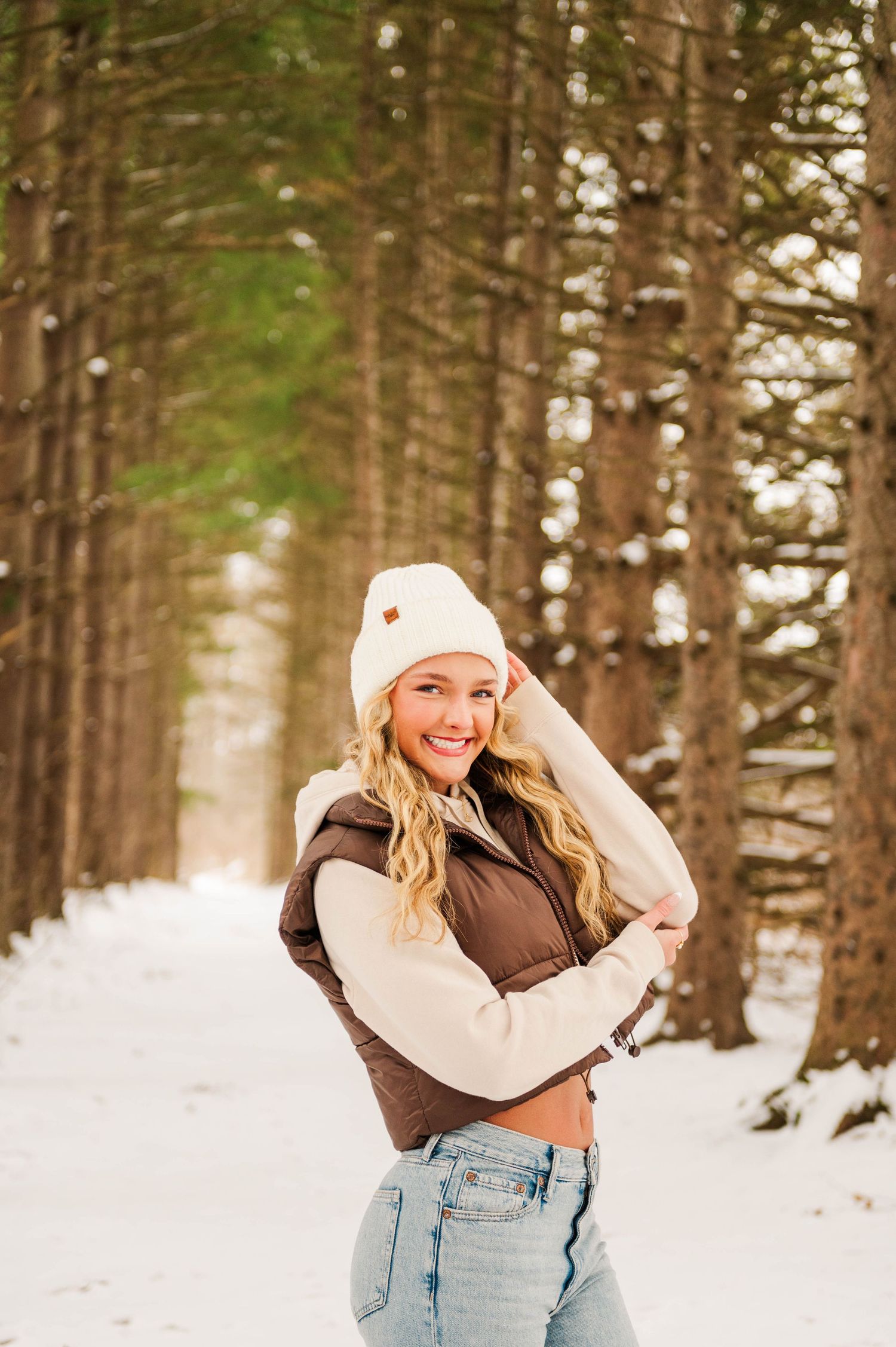 Playful winter portrait session among snow-dusted pine trees in natural lighting.