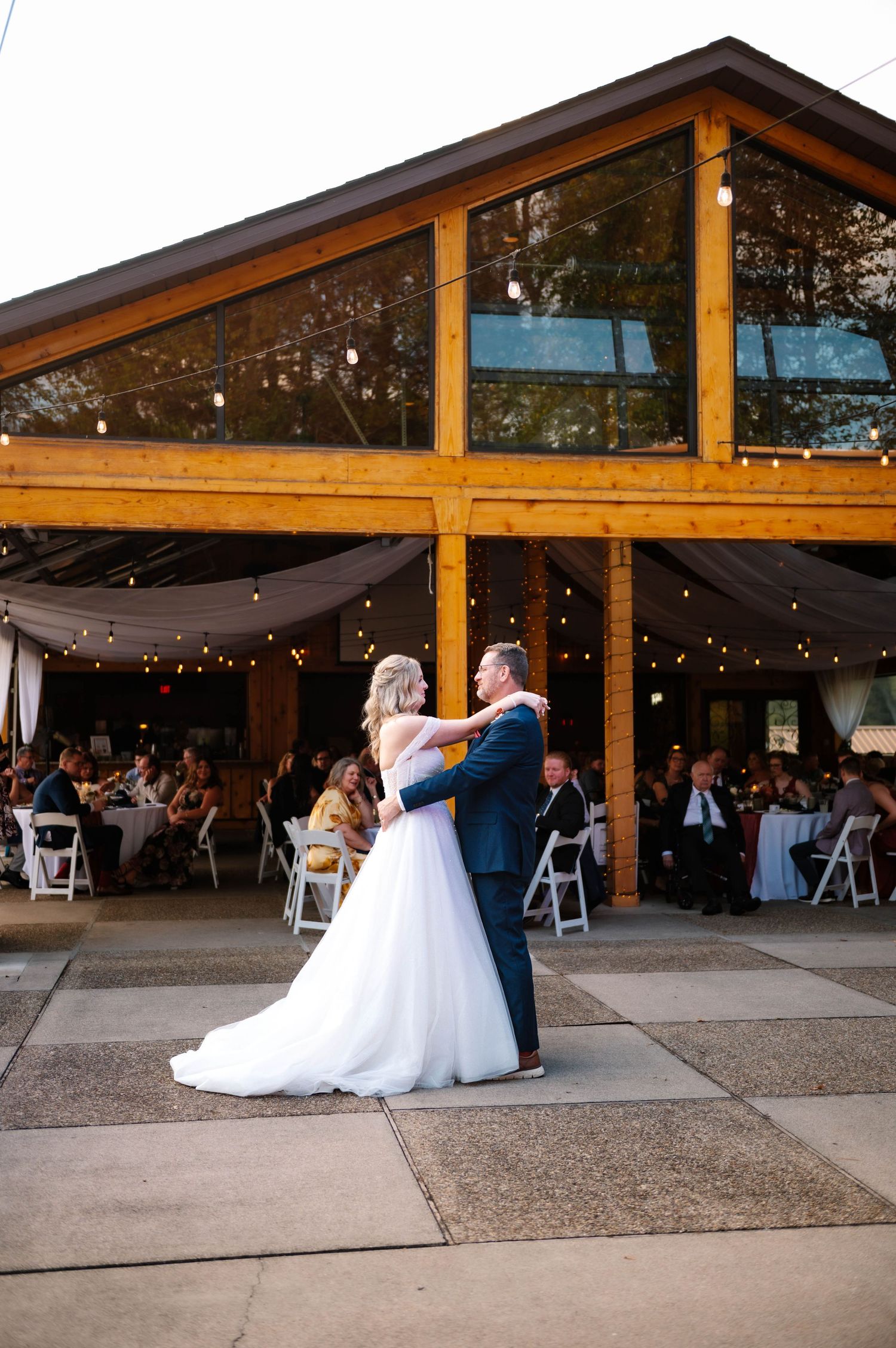 First dance under wooden beamed pavilion at rustic wedding venue.