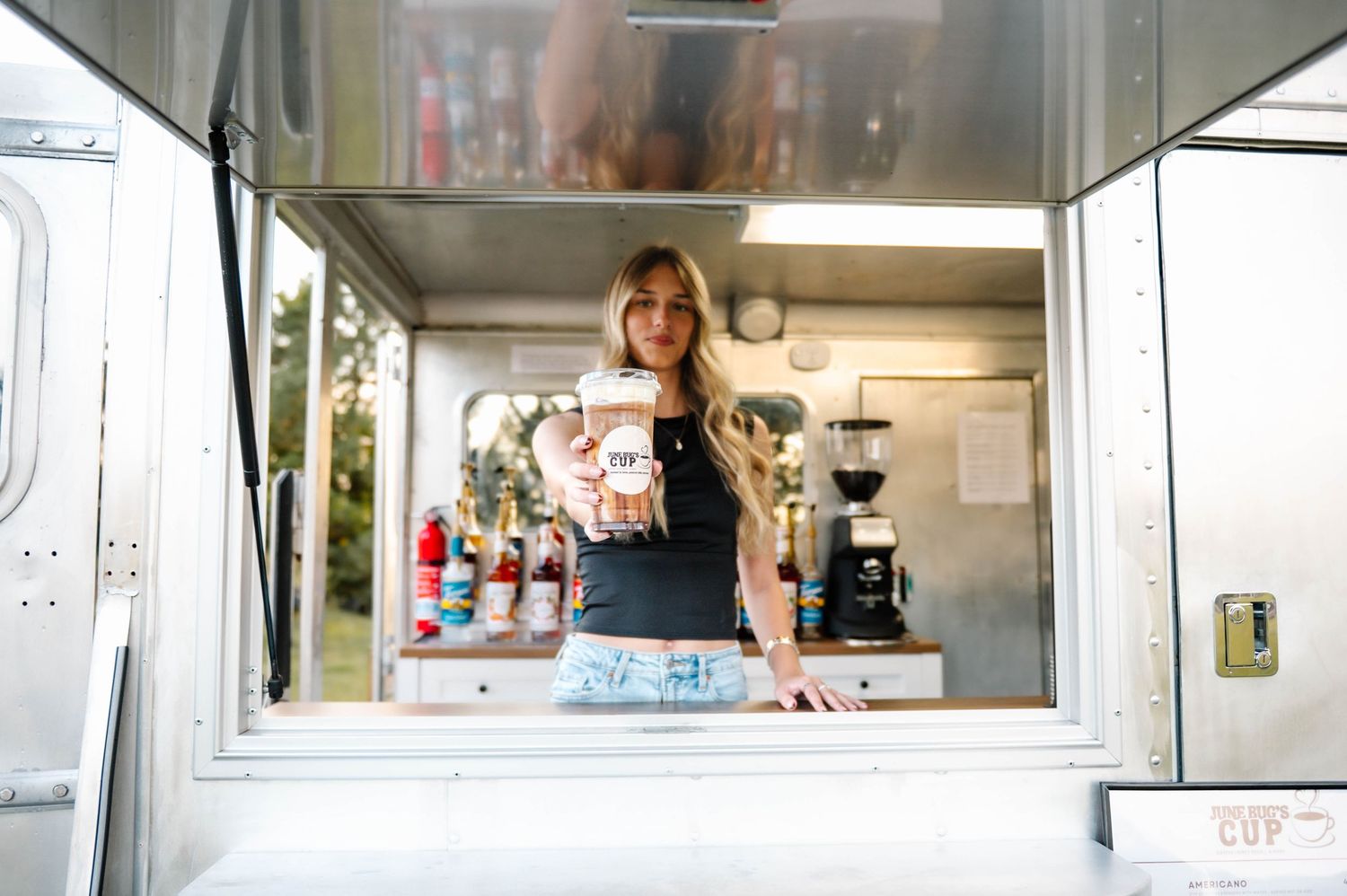 View through service window of coffee truck showing menu board and interior.