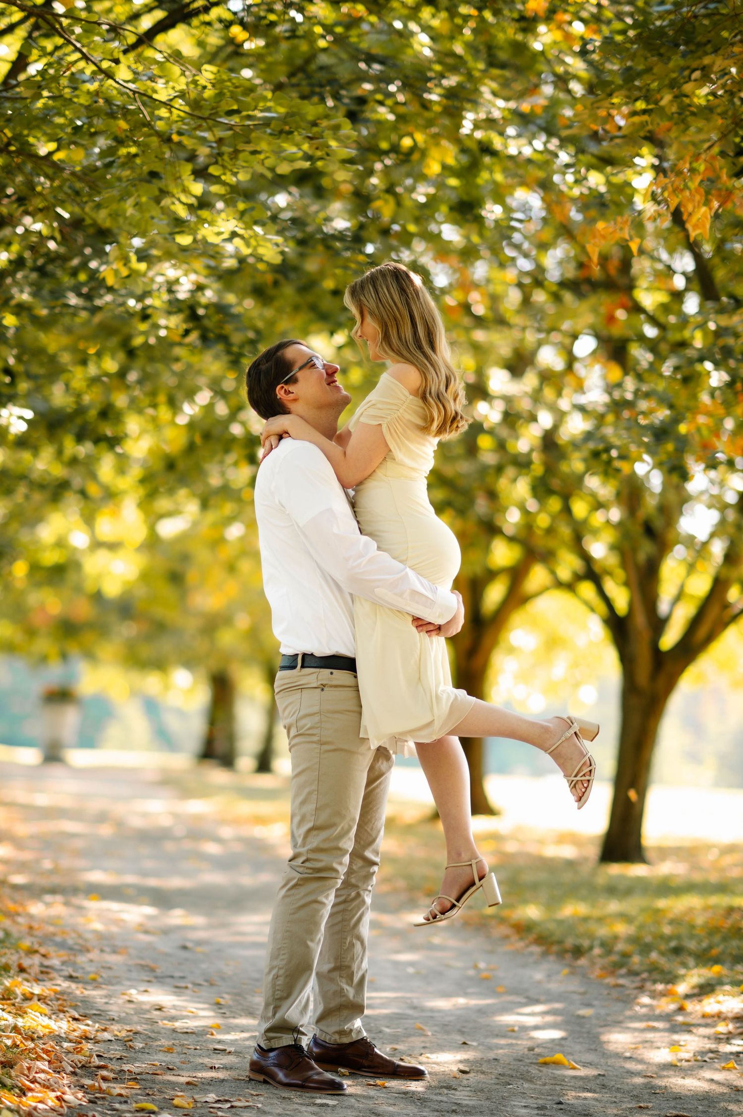 A couple shares joyful spinning moments under autumn trees in golden light.
