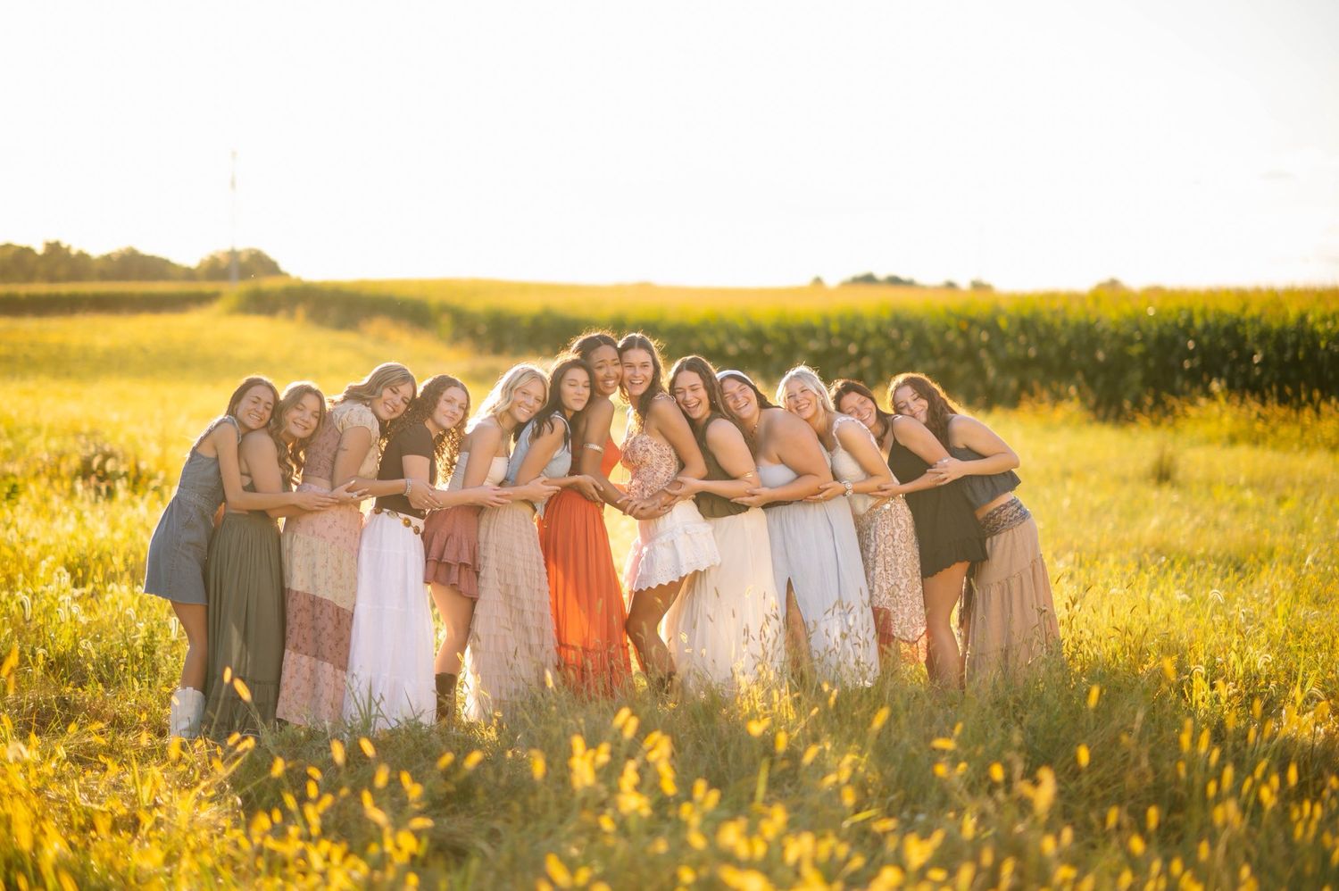 Group forms a circle while holding hands in a sun-soaked summer field.