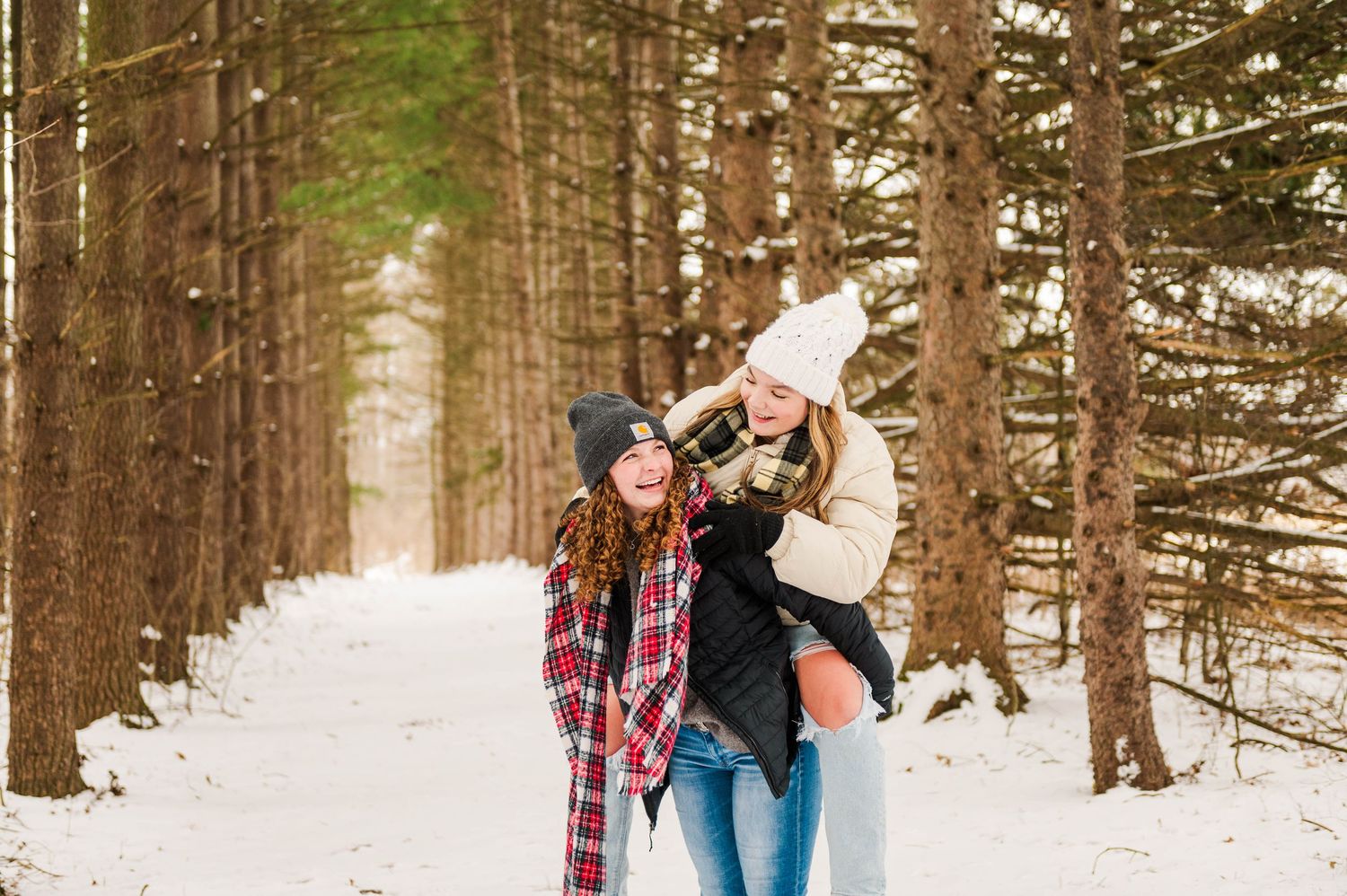 Two friends share a fun piggyback ride moment in a snowy winter forest.