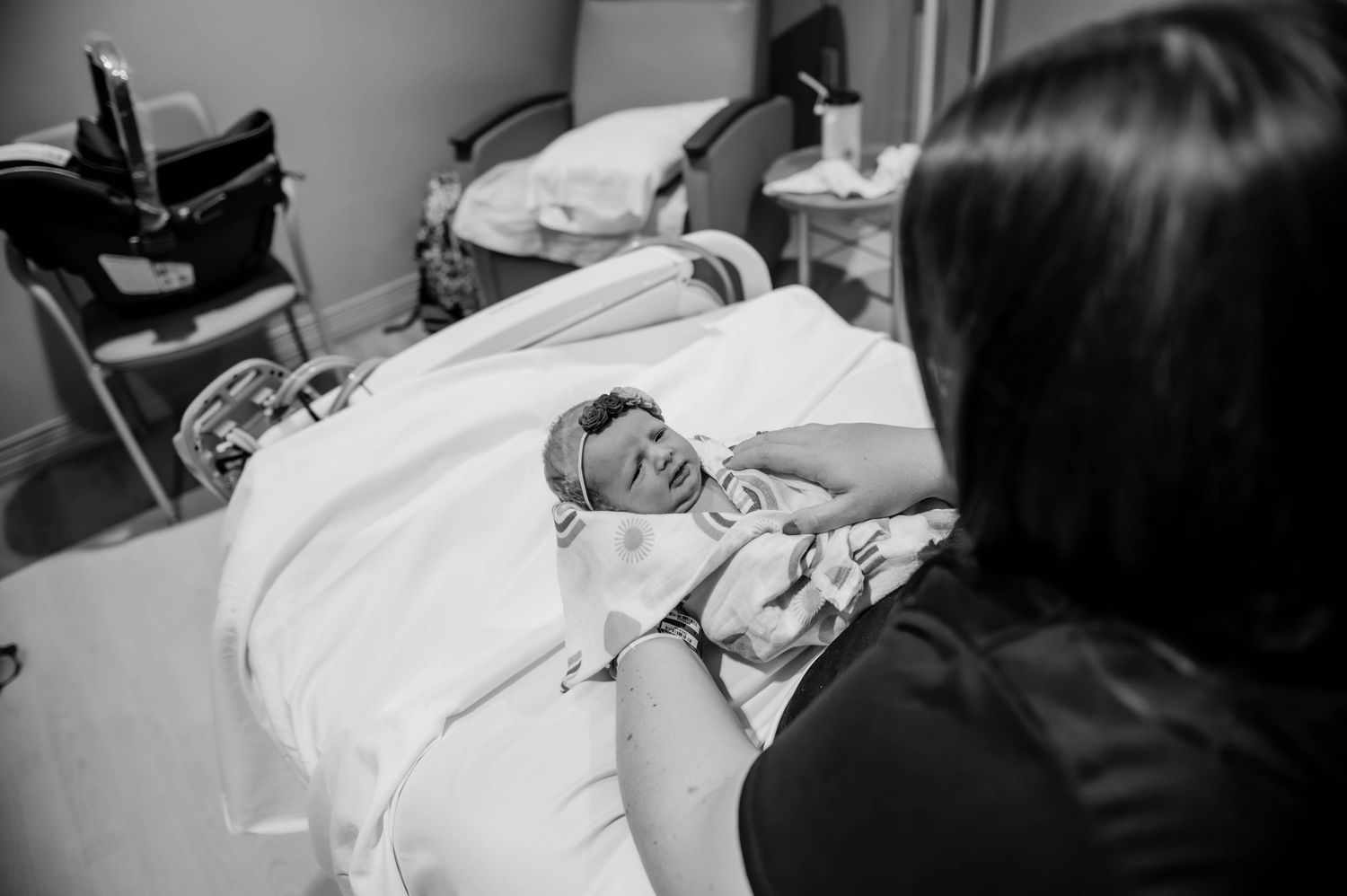 Intimate hospital moment captured in monochrome as a parent tends to their newborn baby.