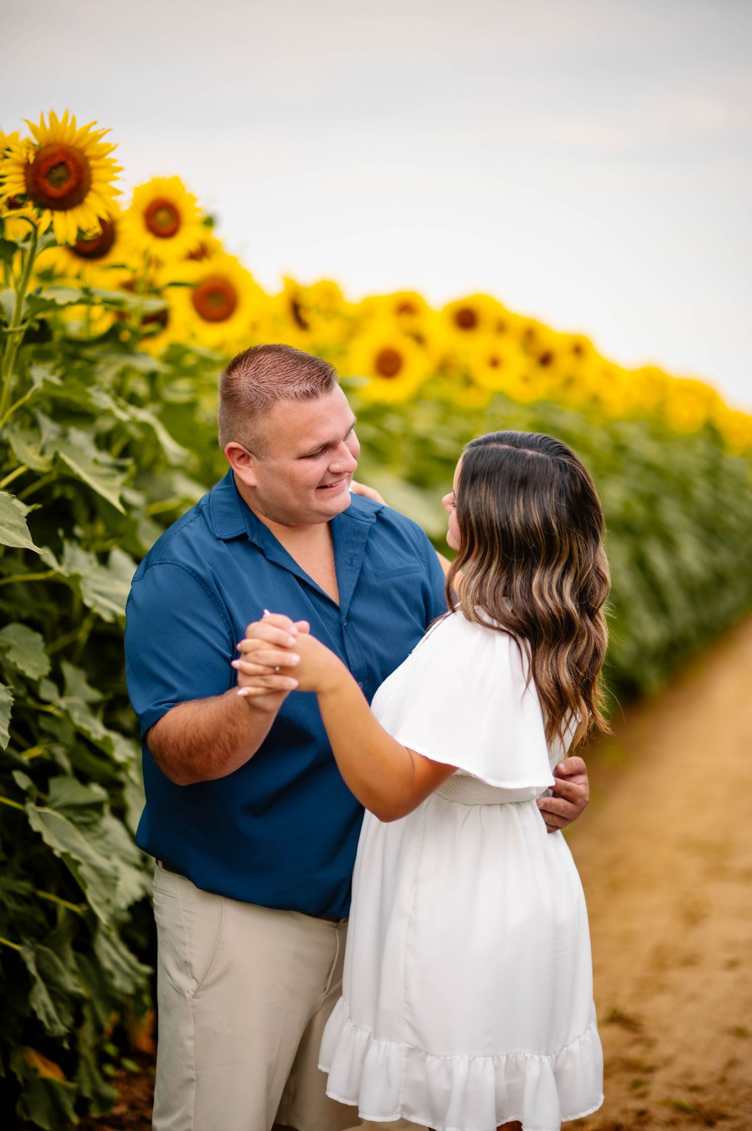 A couple dancing together in a beautiful sunflower field during golden hour.