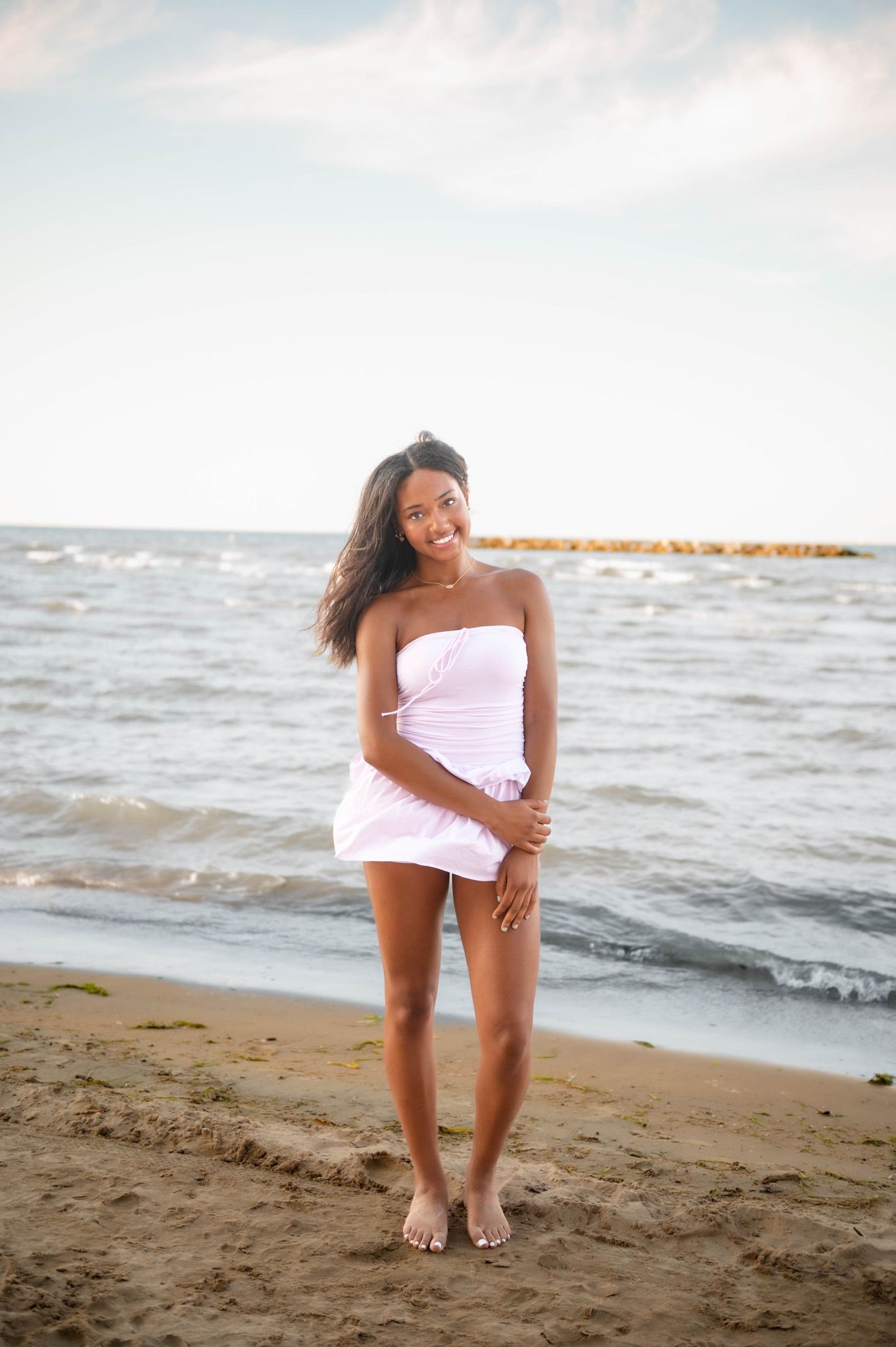 Candid beach photoshoot with person in white outfit against waves.