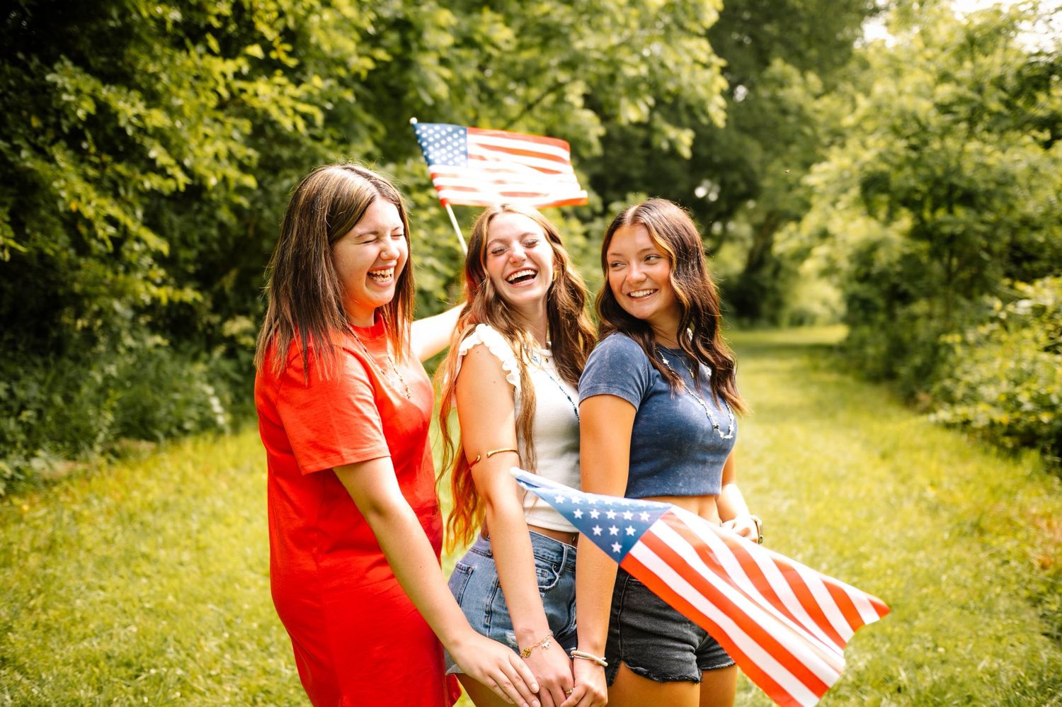 Friends in red white and blue outfits celebrating together on a grassy field.