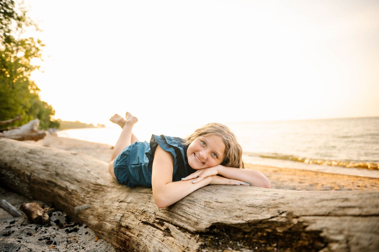 Sunset beach portrait on driftwood with ocean backdrop.