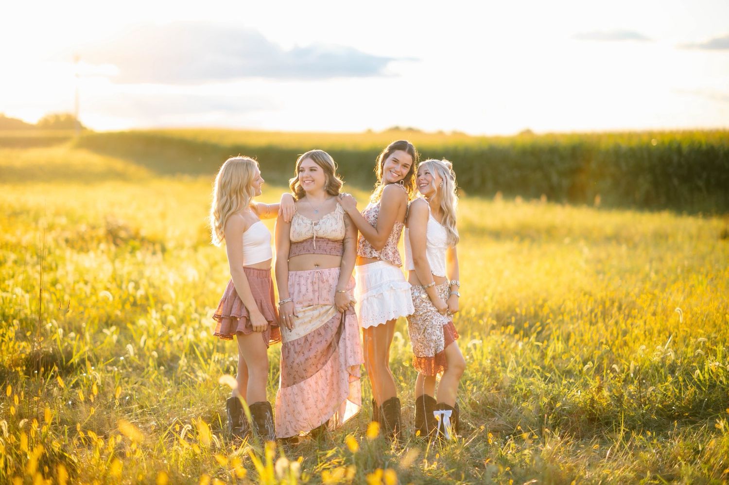 Small group laughing together in a sun-drenched summer field.