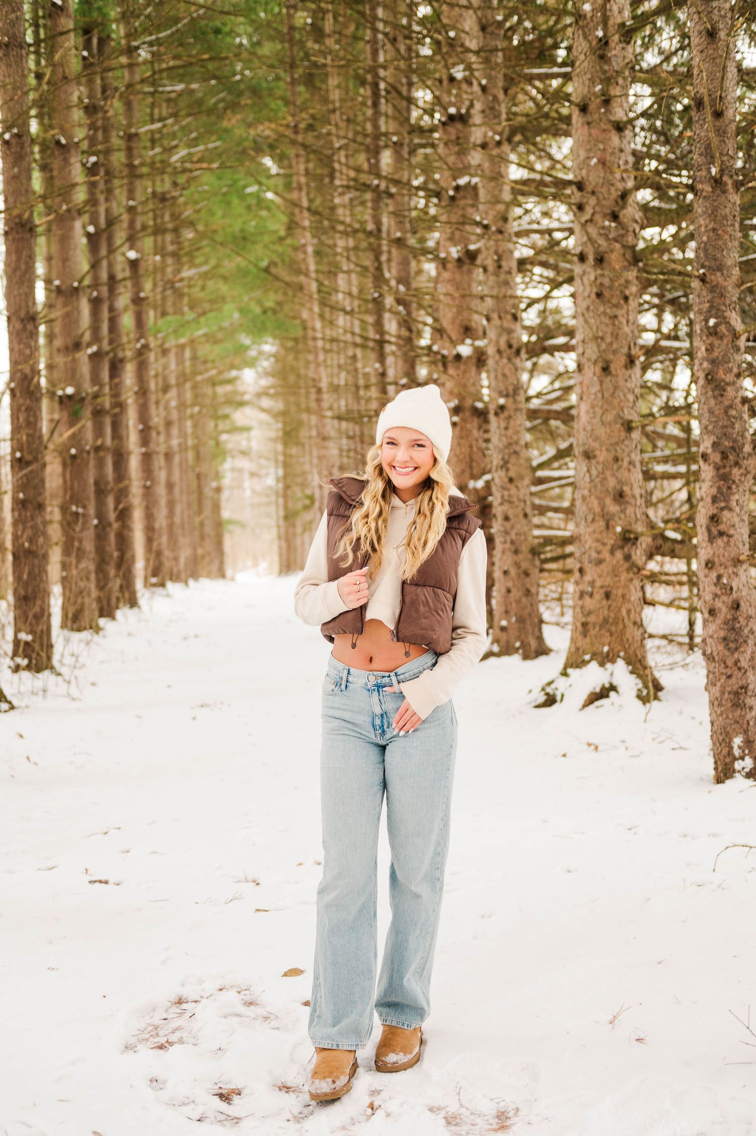 Casual winter outfit photos featuring denim and brown jacket in snowy pine forest.