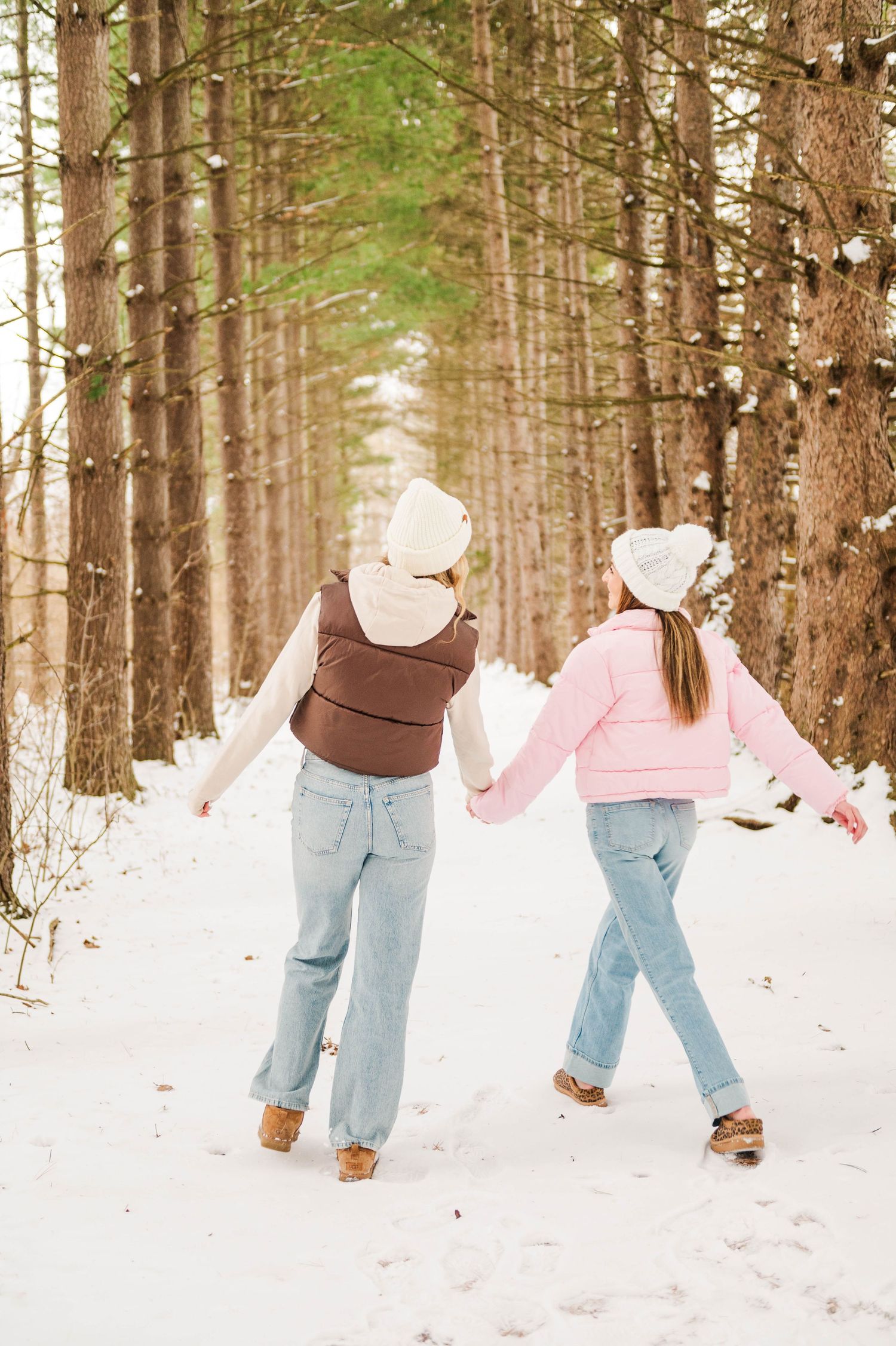 People walking through a snowy forest wearing matching jeans and winter coats.