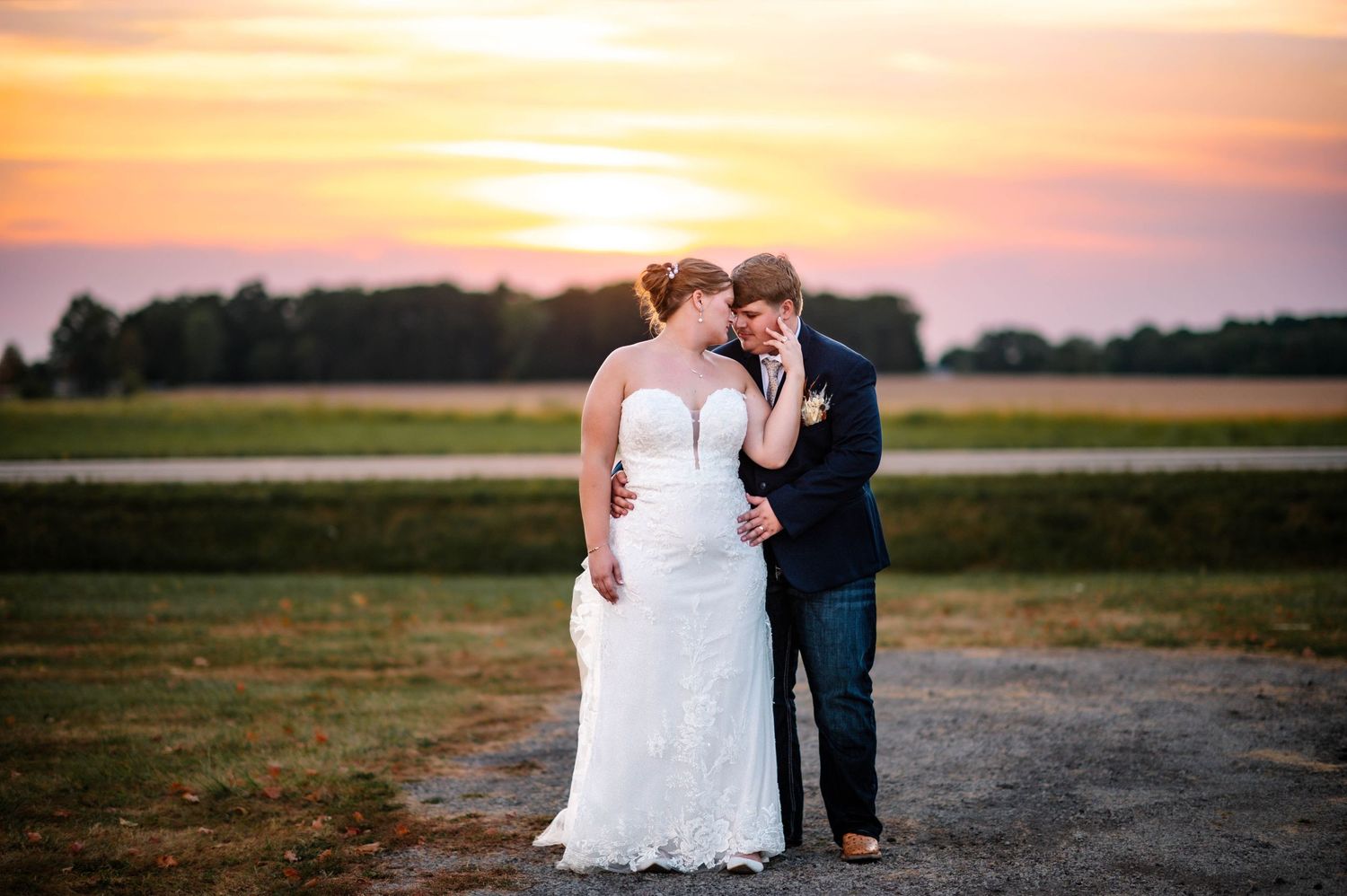 Romantic sunset wedding portraits captured against an orange sky.