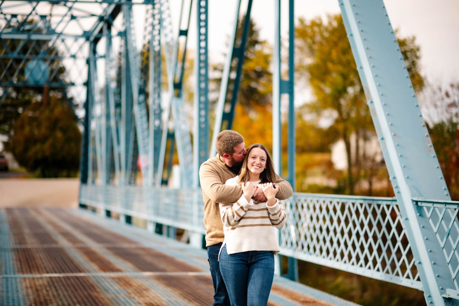 Historic blue metal bridge creates scenic backdrop for romantic photoshoot.