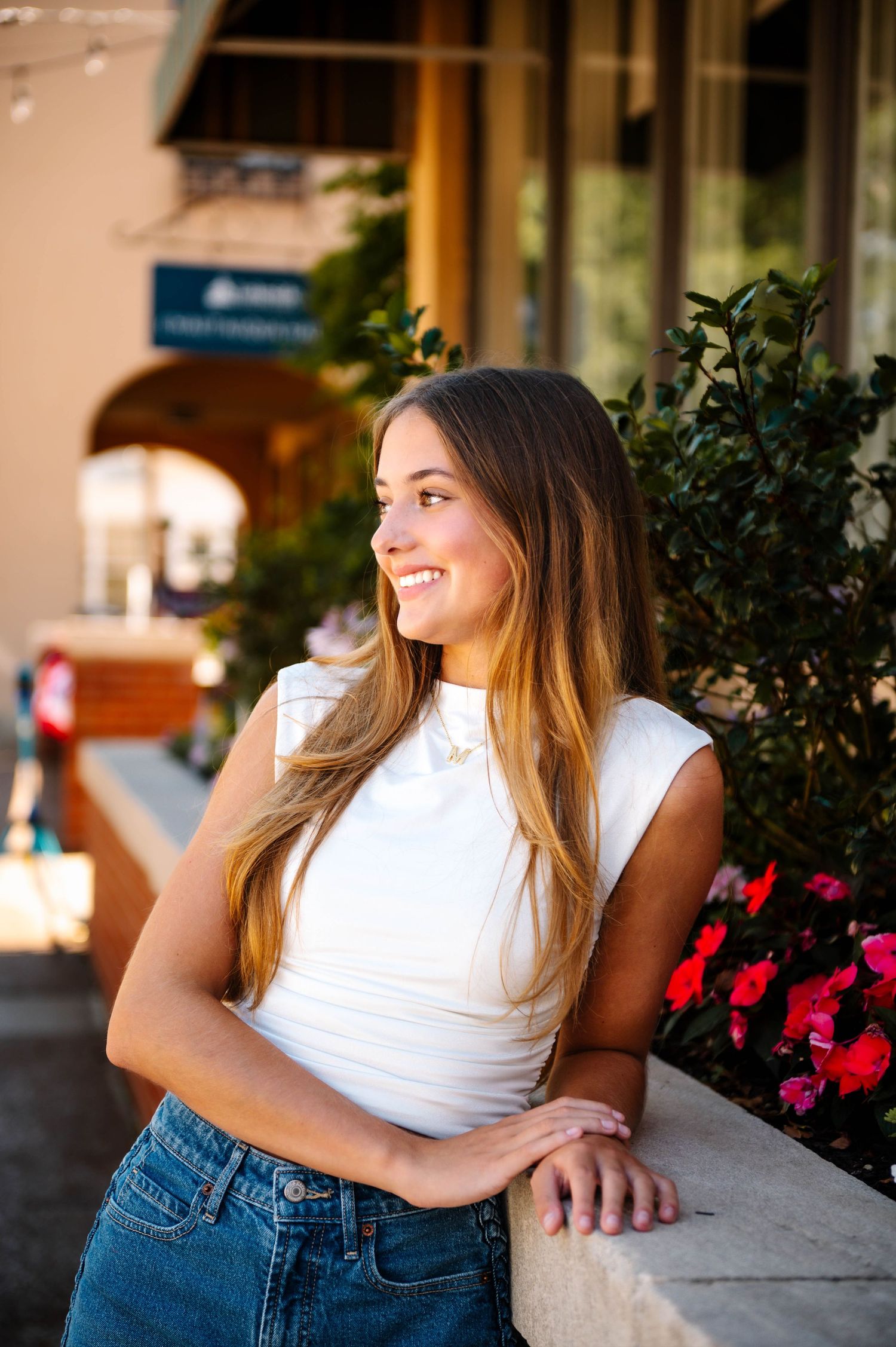 Casual summer portrait against a storefront with red flowers and greenery.