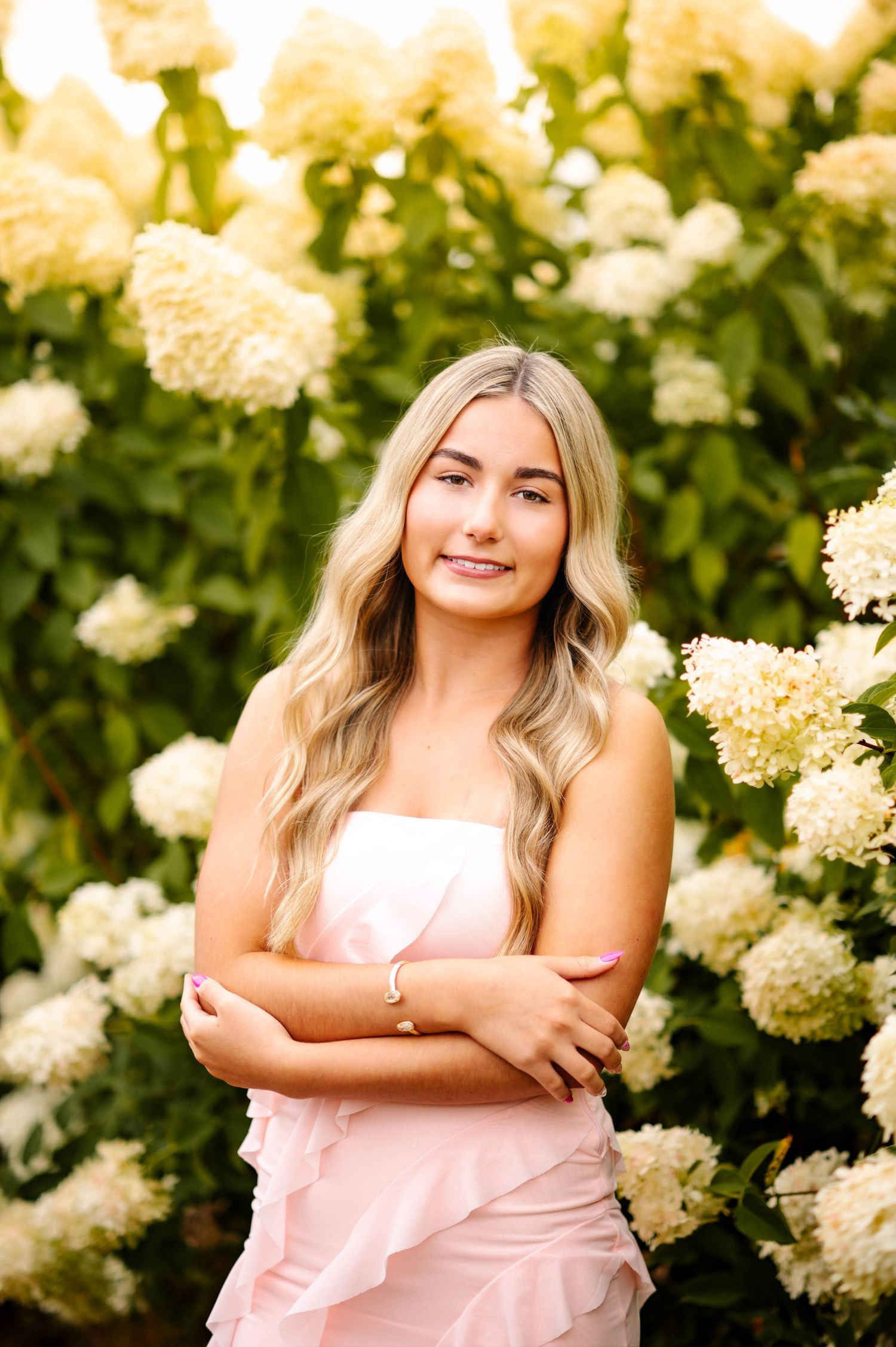 Elegant outdoor portrait session among blooming white hydrangea bushes in soft natural lighting.