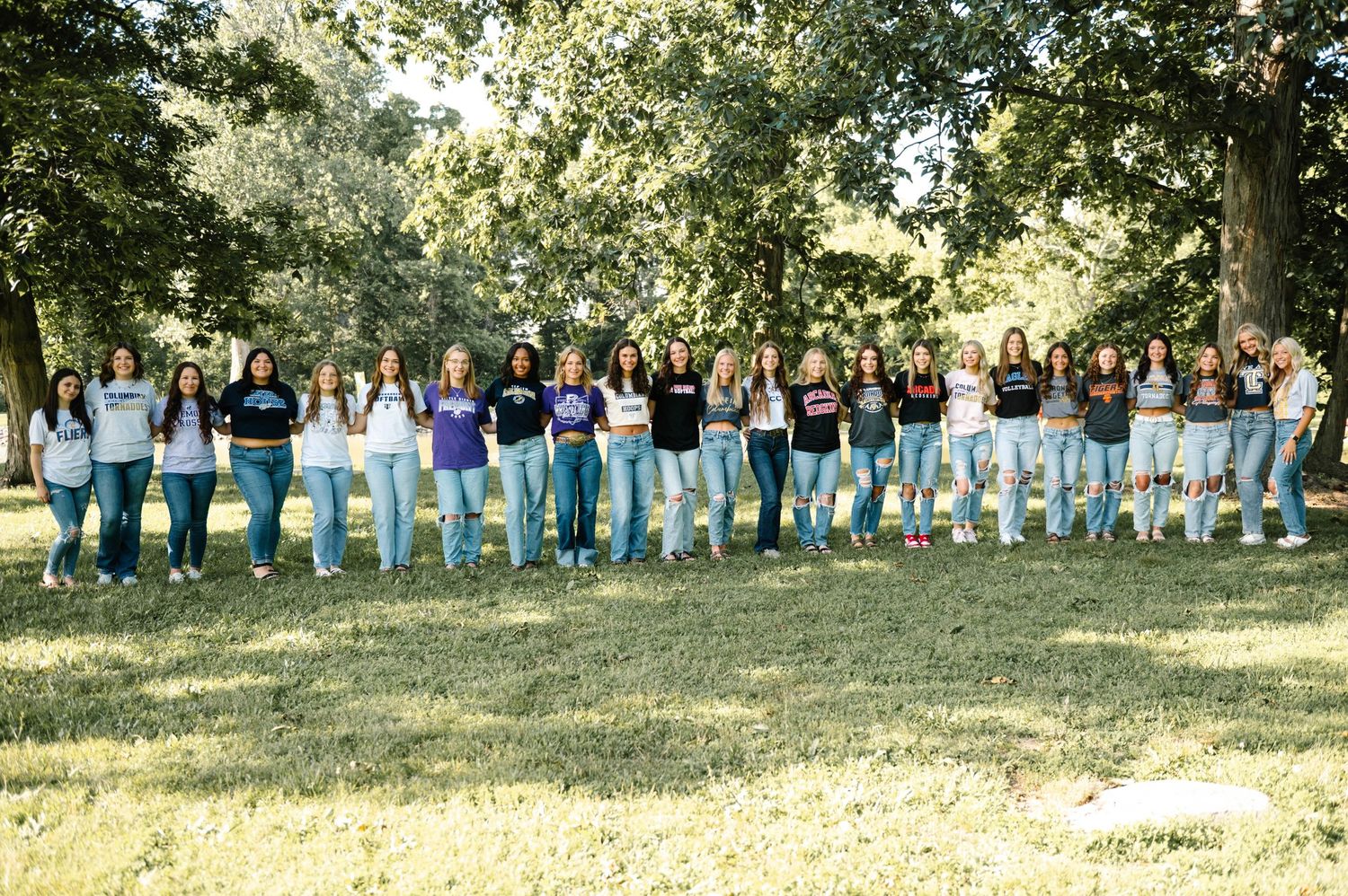 Panoramic group photo showing people lined up in casual attire against a natural outdoor background.