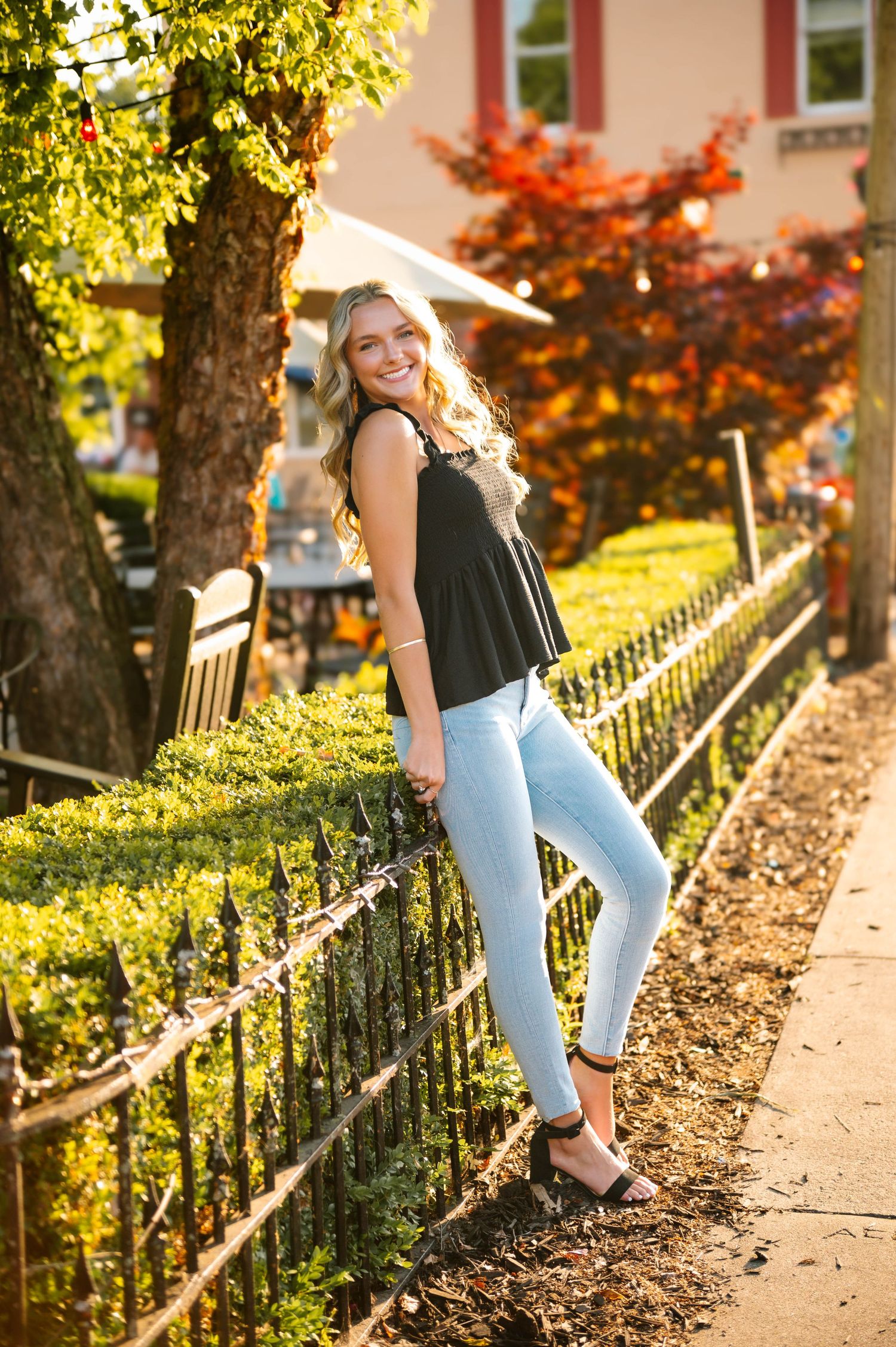Outdoor portrait session along garden path with autumn foliage and iron railing.