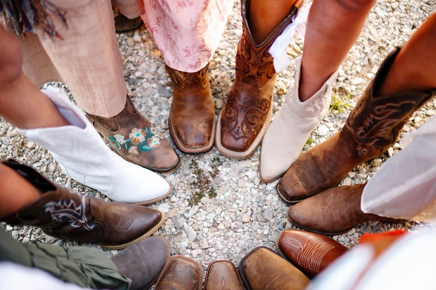 Brown cowboy boots line up on a gravel path showing rustic country style.