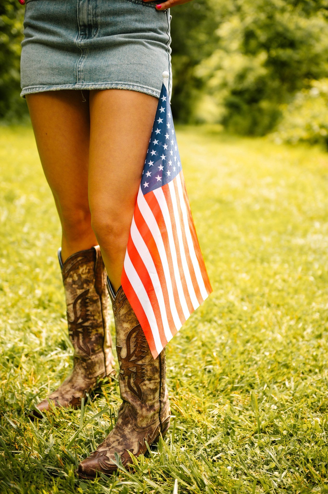 Cowboy boots and American flags displayed in green summer grass.
