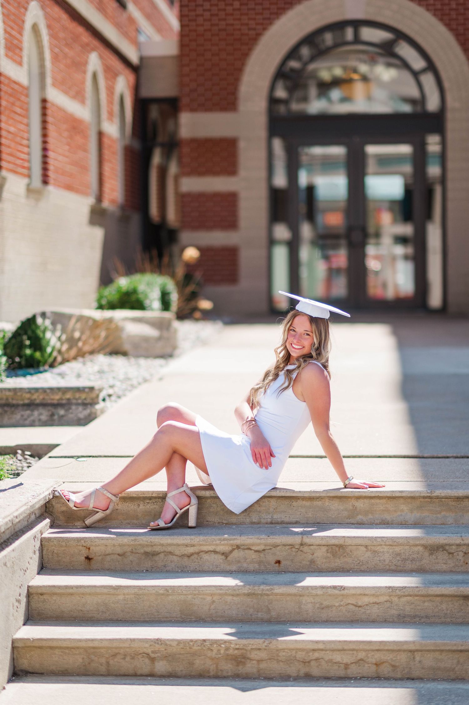 Relaxed graduation photos on concrete steps in bright sunlight.