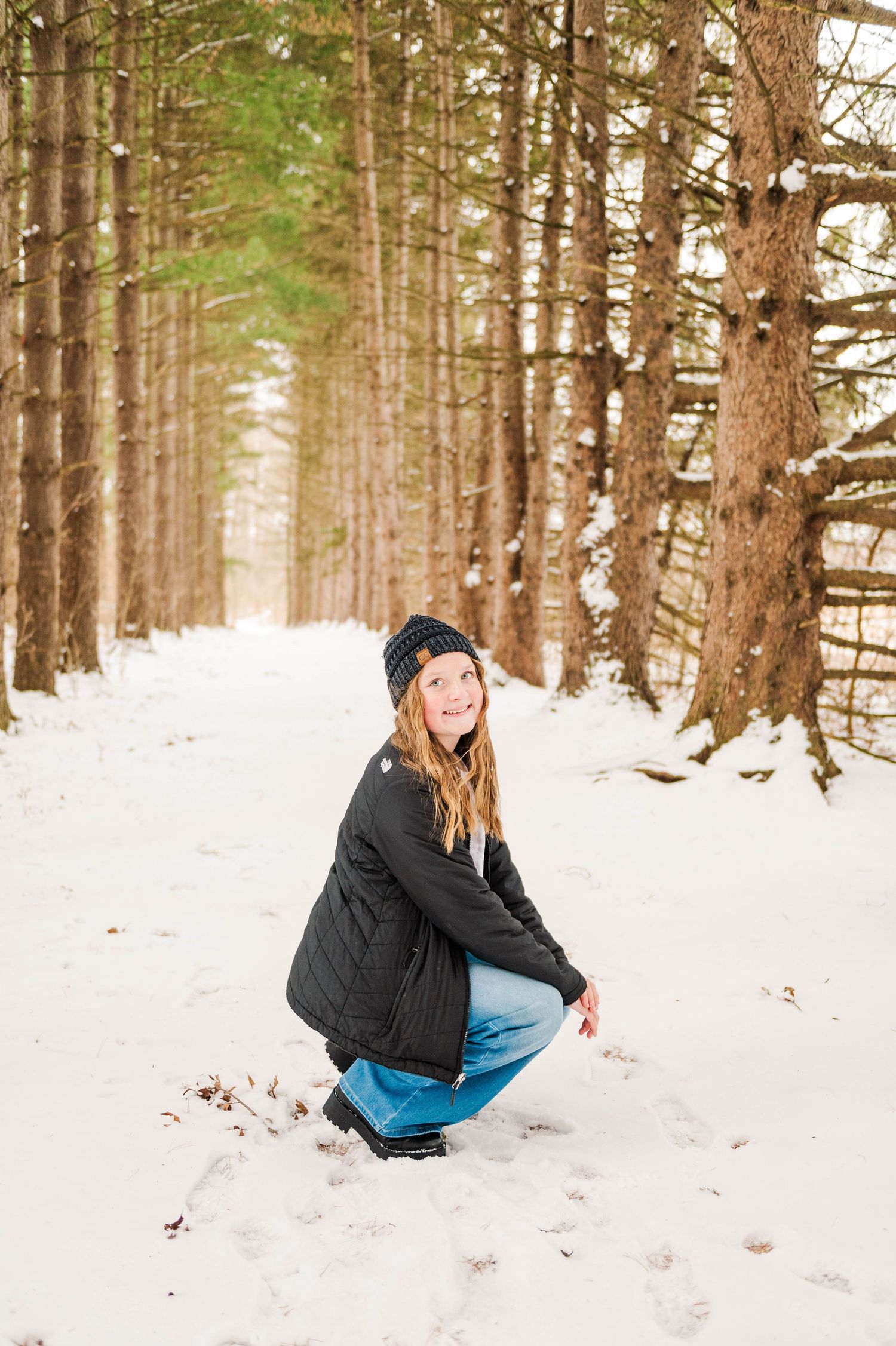 Casual winter portraits taken in a scenic snow-covered pine forest.