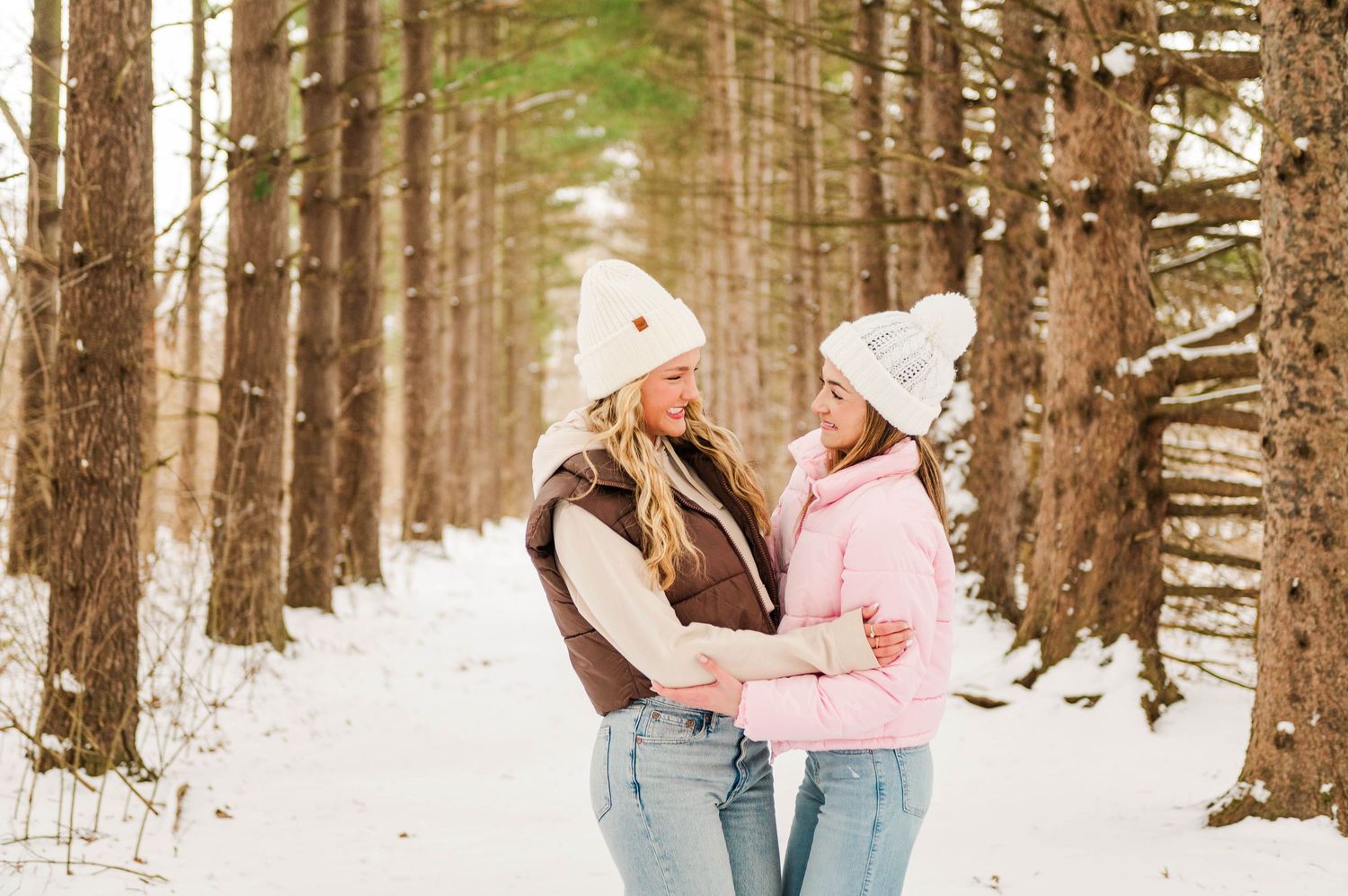 Winter forest scene with people walking through snow-covered pine trees.
