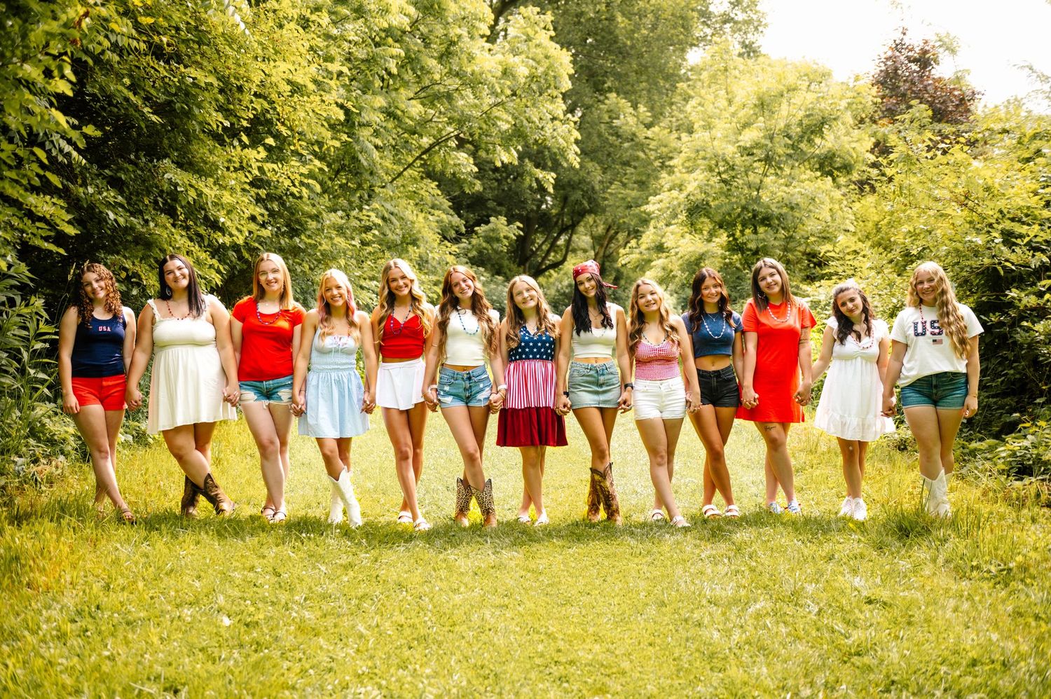 A group wearing red white and blue outfits poses together in a summer field.