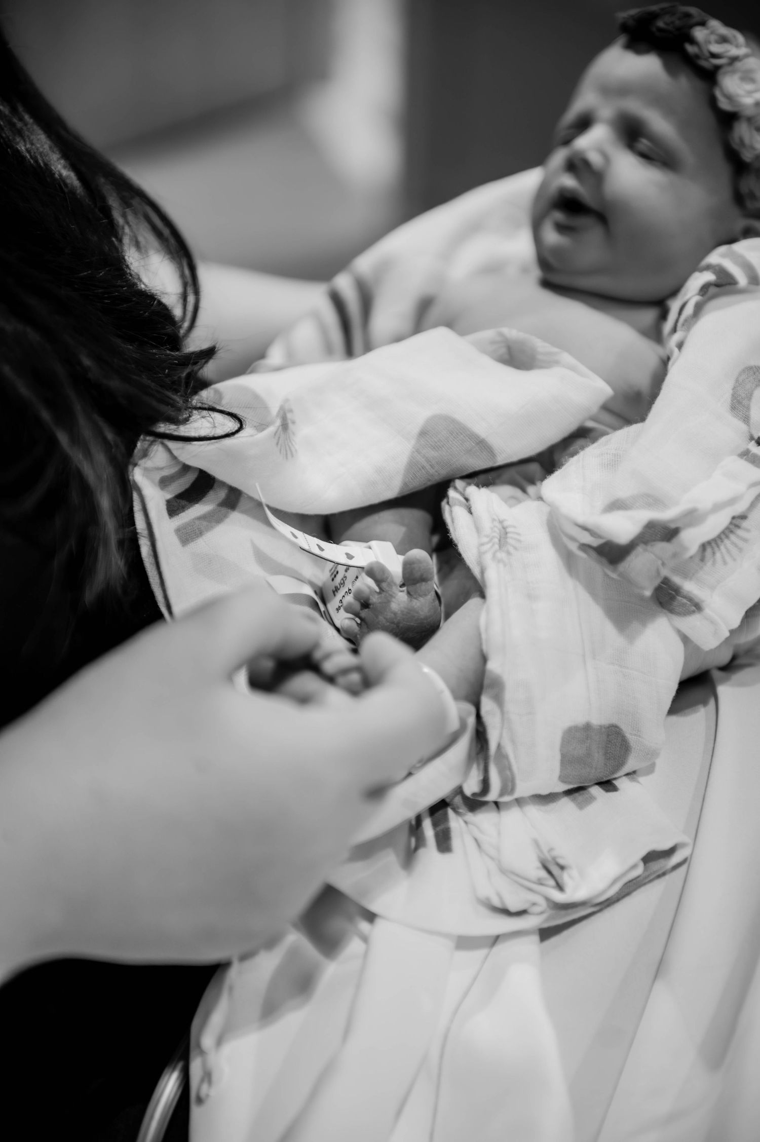 Healthcare provider examining a newborn baby wrapped in a patterned blanket.