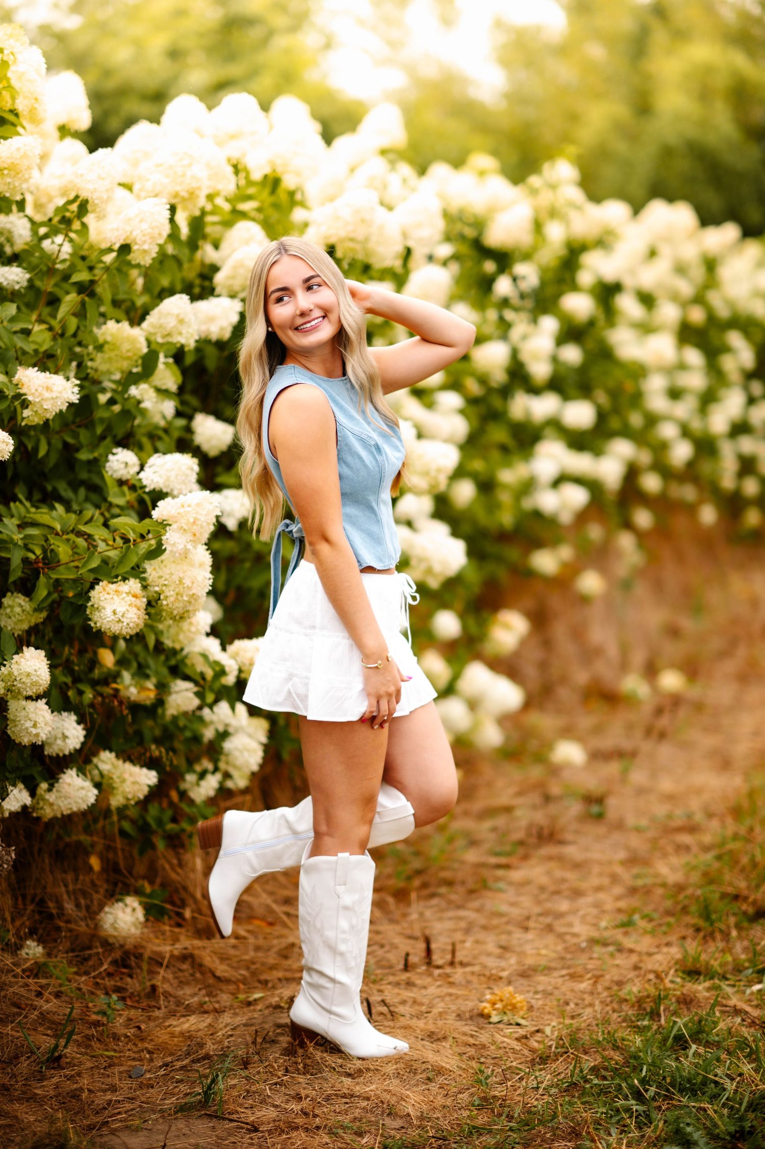 Playful poses captured along a path lined with cream-colored blooming roses.