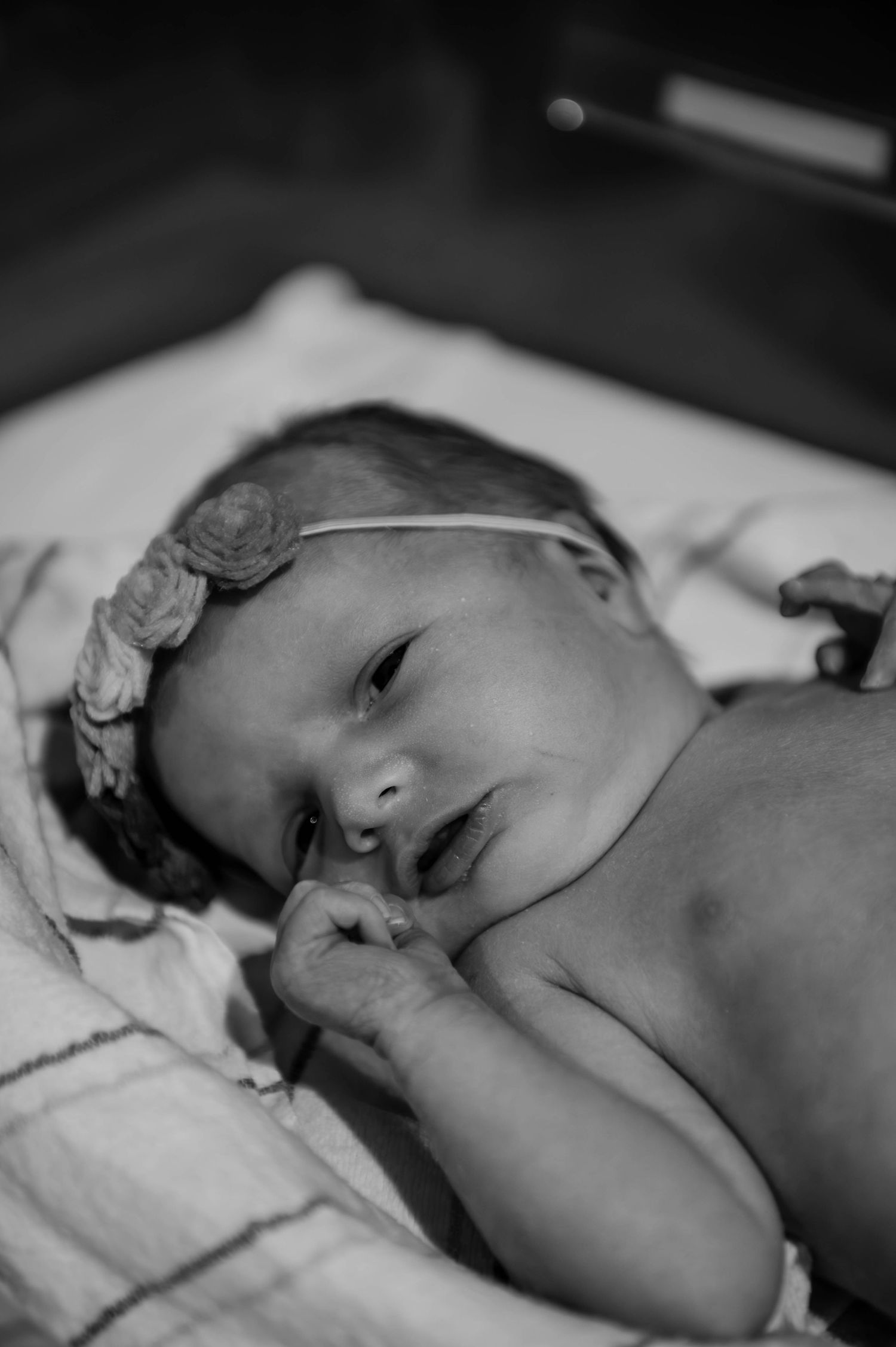 A small infant rests in a medical bassinet while being monitored with hospital equipment.