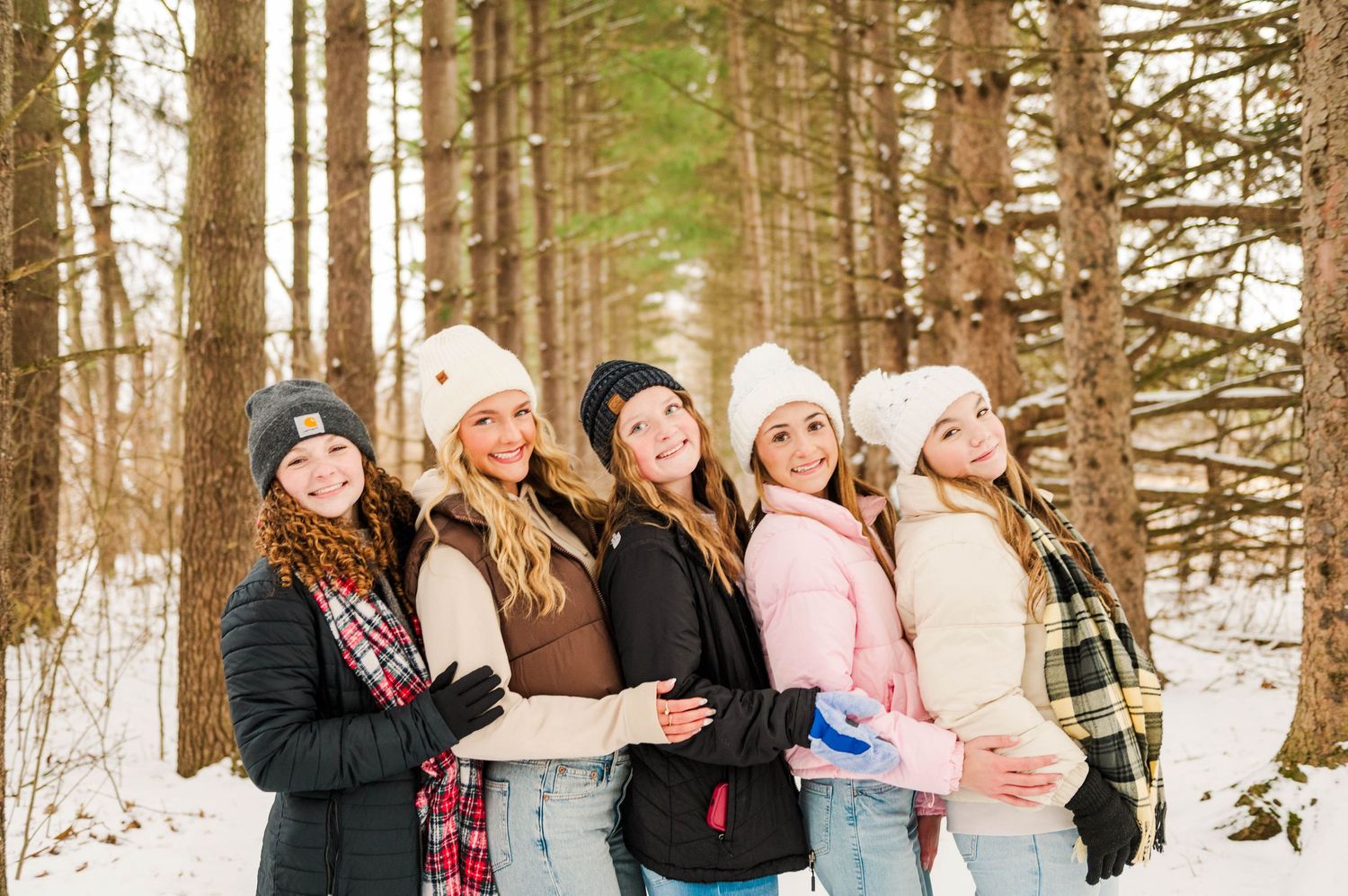 Friends gathered for a winter photoshoot in the woods wearing coordinated casual attire.