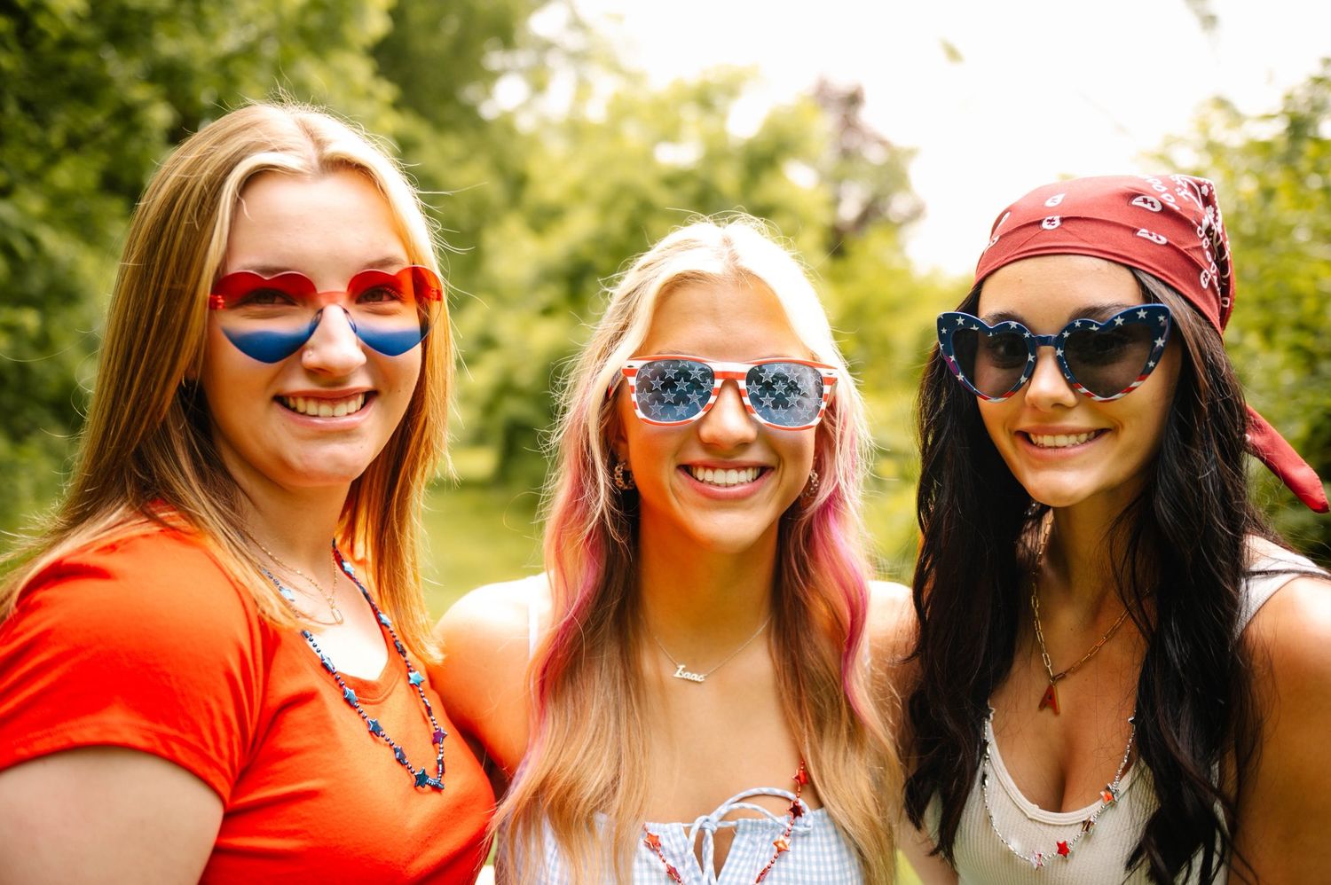 Group wearing patriotic sunglasses poses together outdoors.