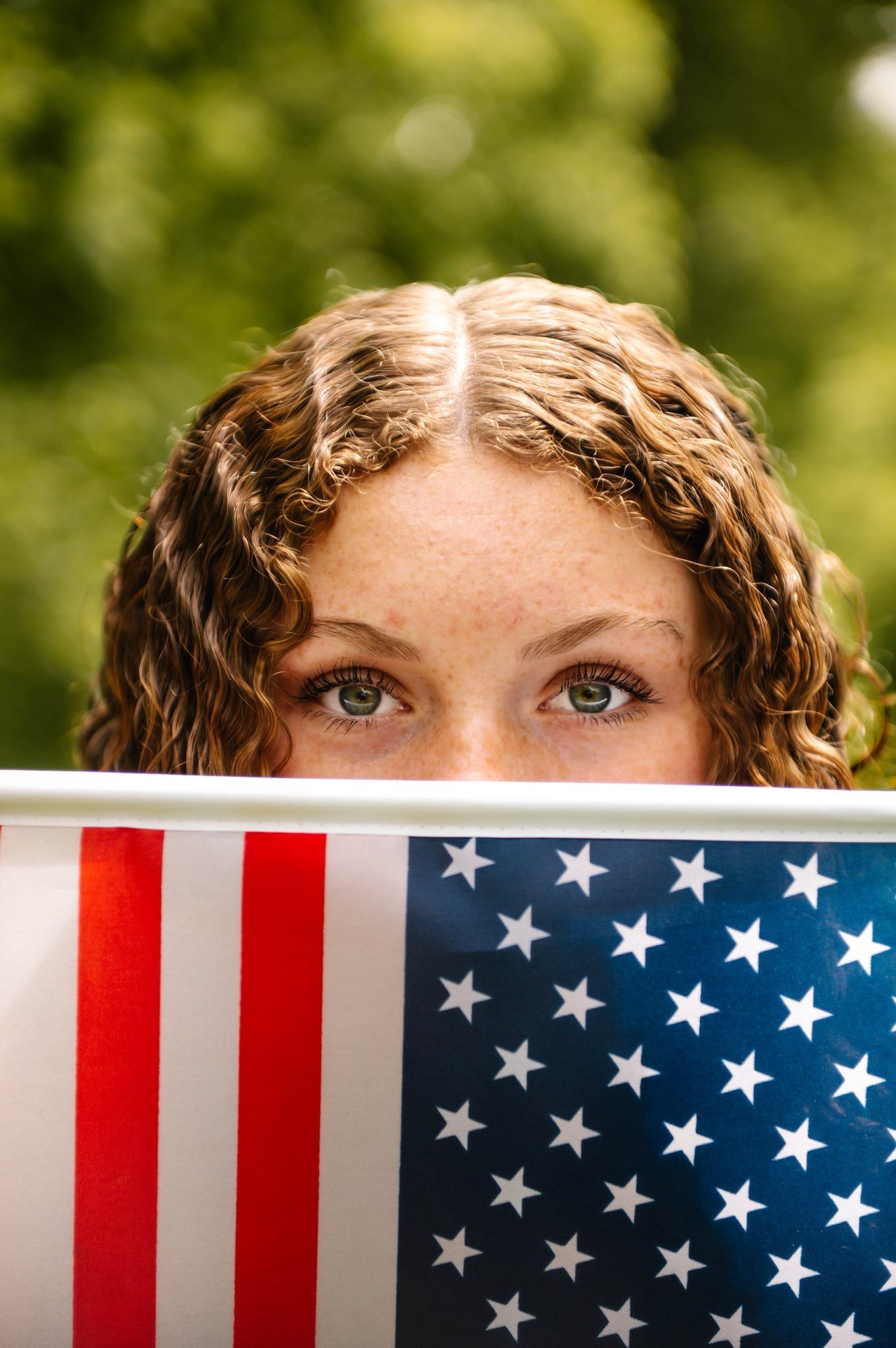 Close up view of American flag with blurred green background.