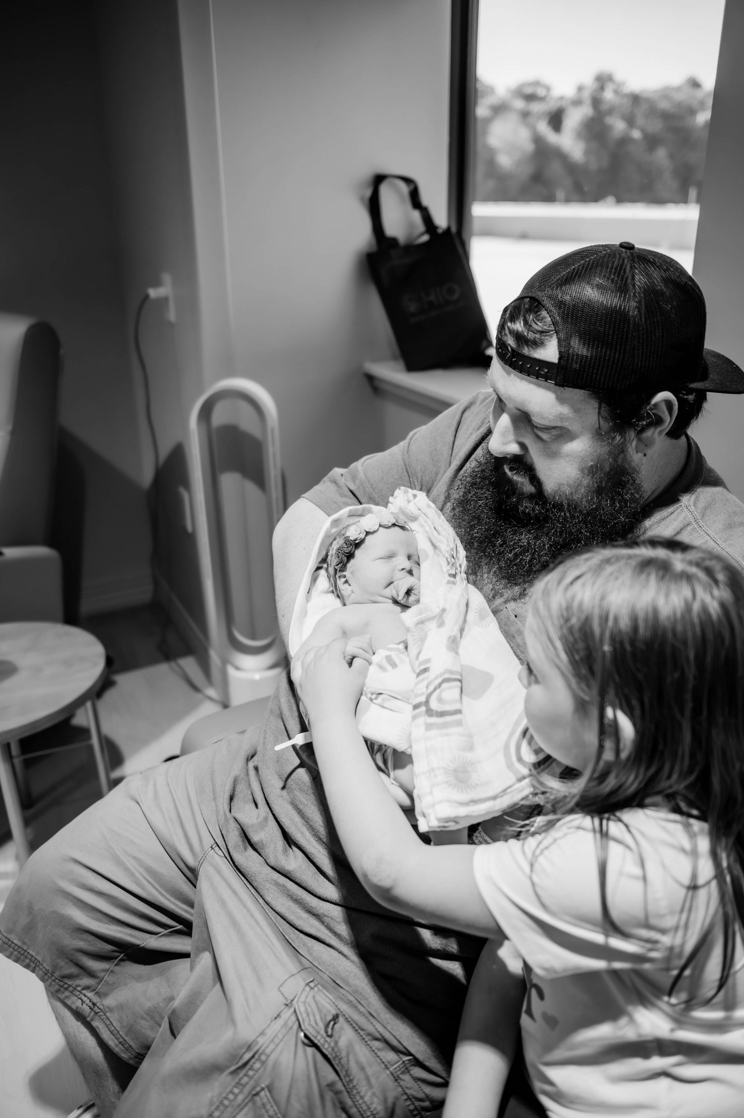 Black and white image showing intimate family interaction on a couch.
