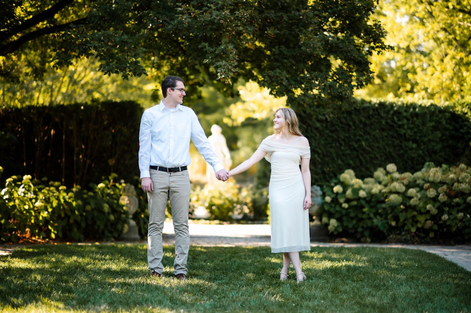 A couple walks together through a sunlit garden path during golden hour.