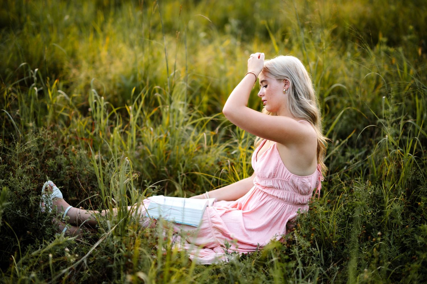 Artistic portrait in pink dress surrounded by wild summer grasses.