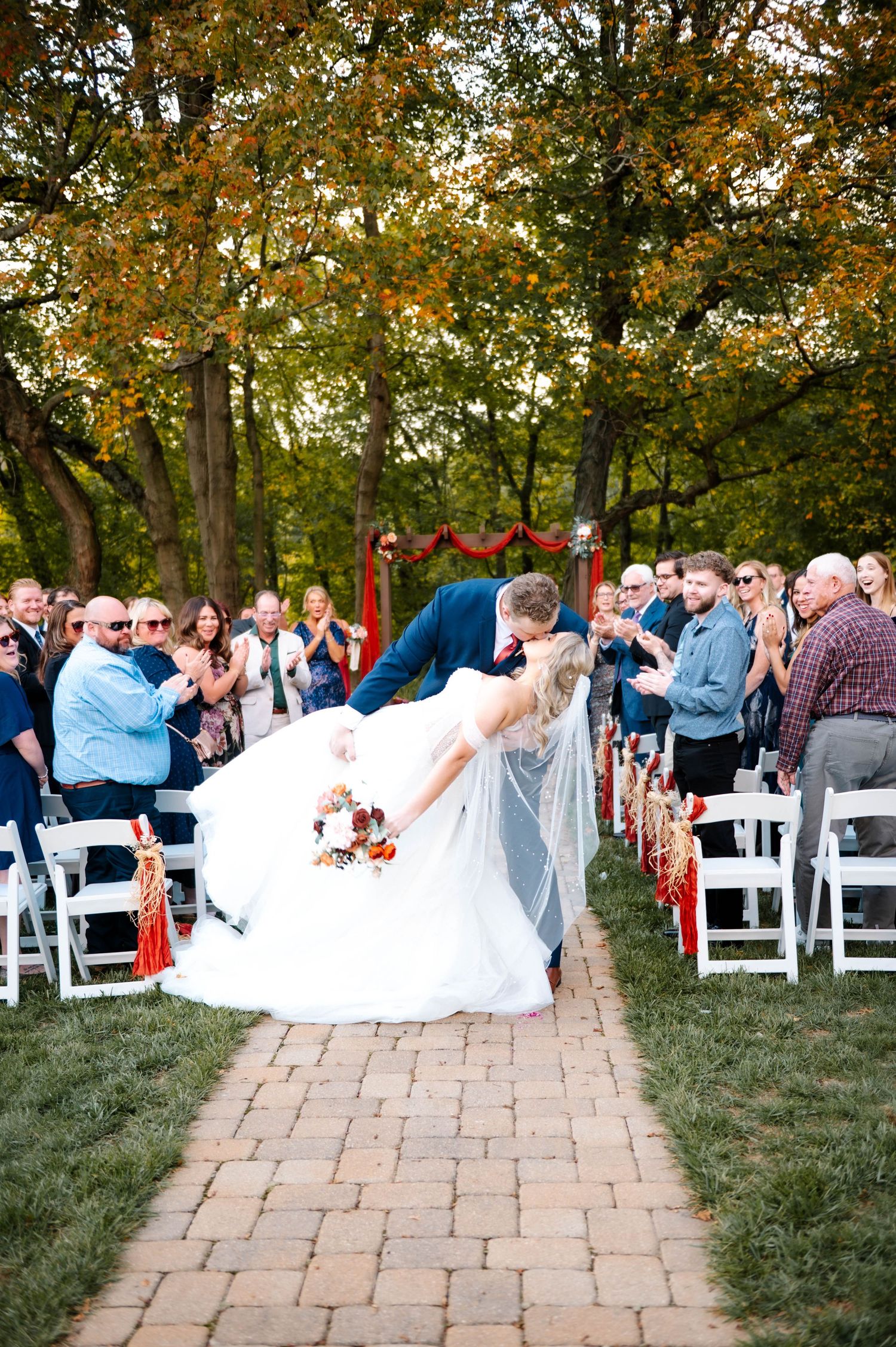 Wedding ceremony exit with guests seated on white chairs along stone pathway.
