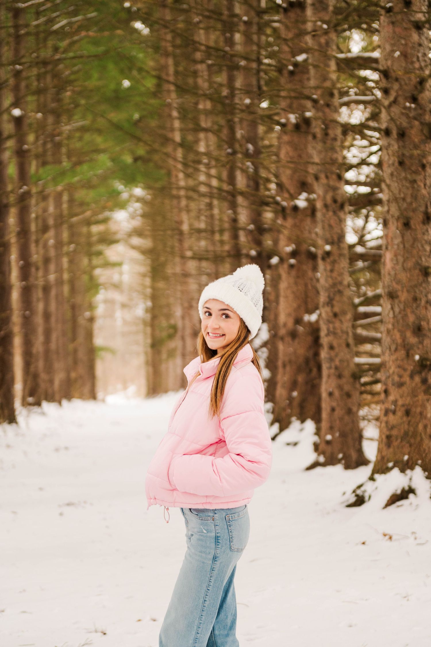 A winter outdoor portrait session featuring casual winter attire against snow-covered evergreens.