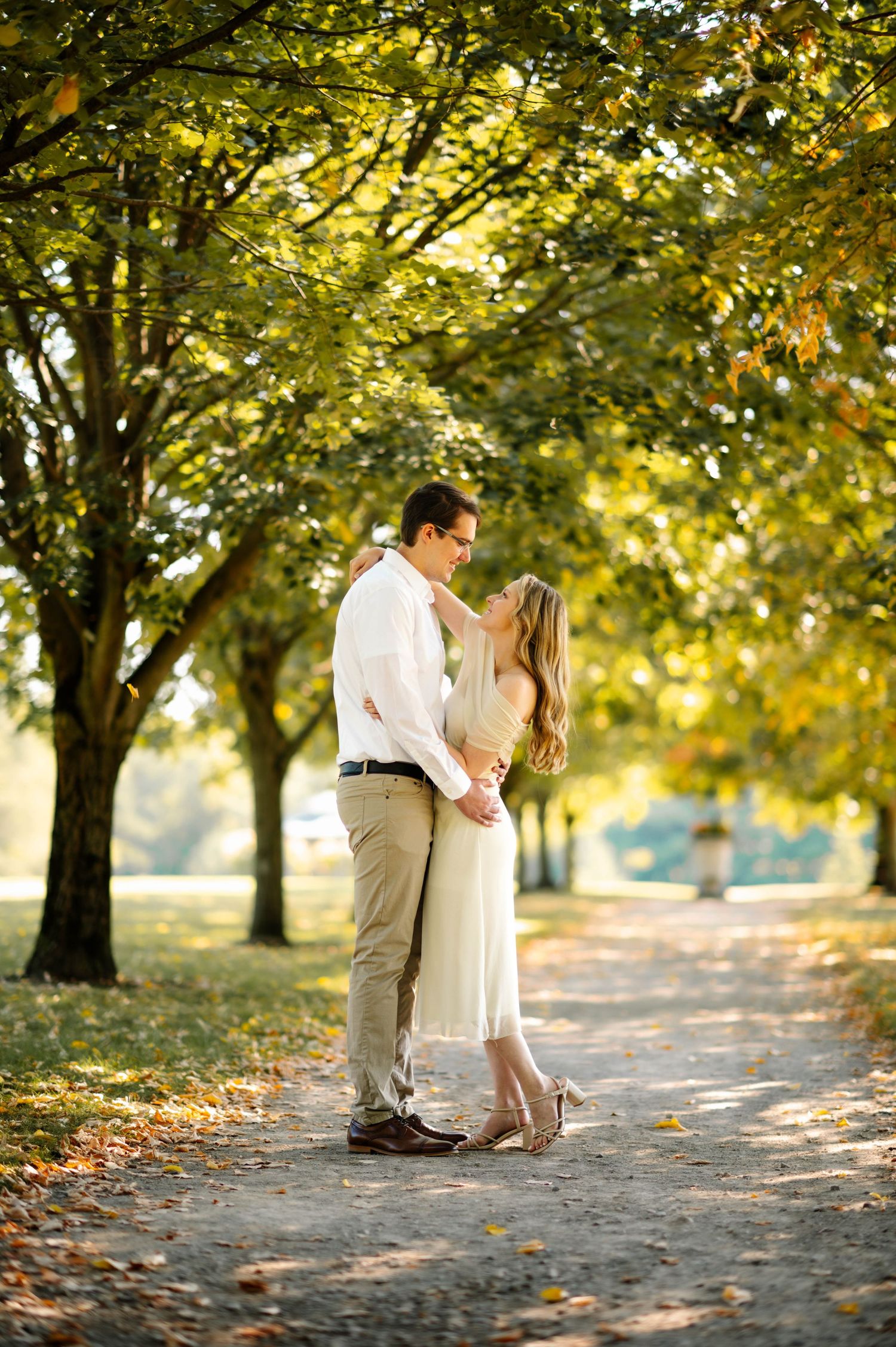 A romantic couple shares tender moments under autumn trees in a park.