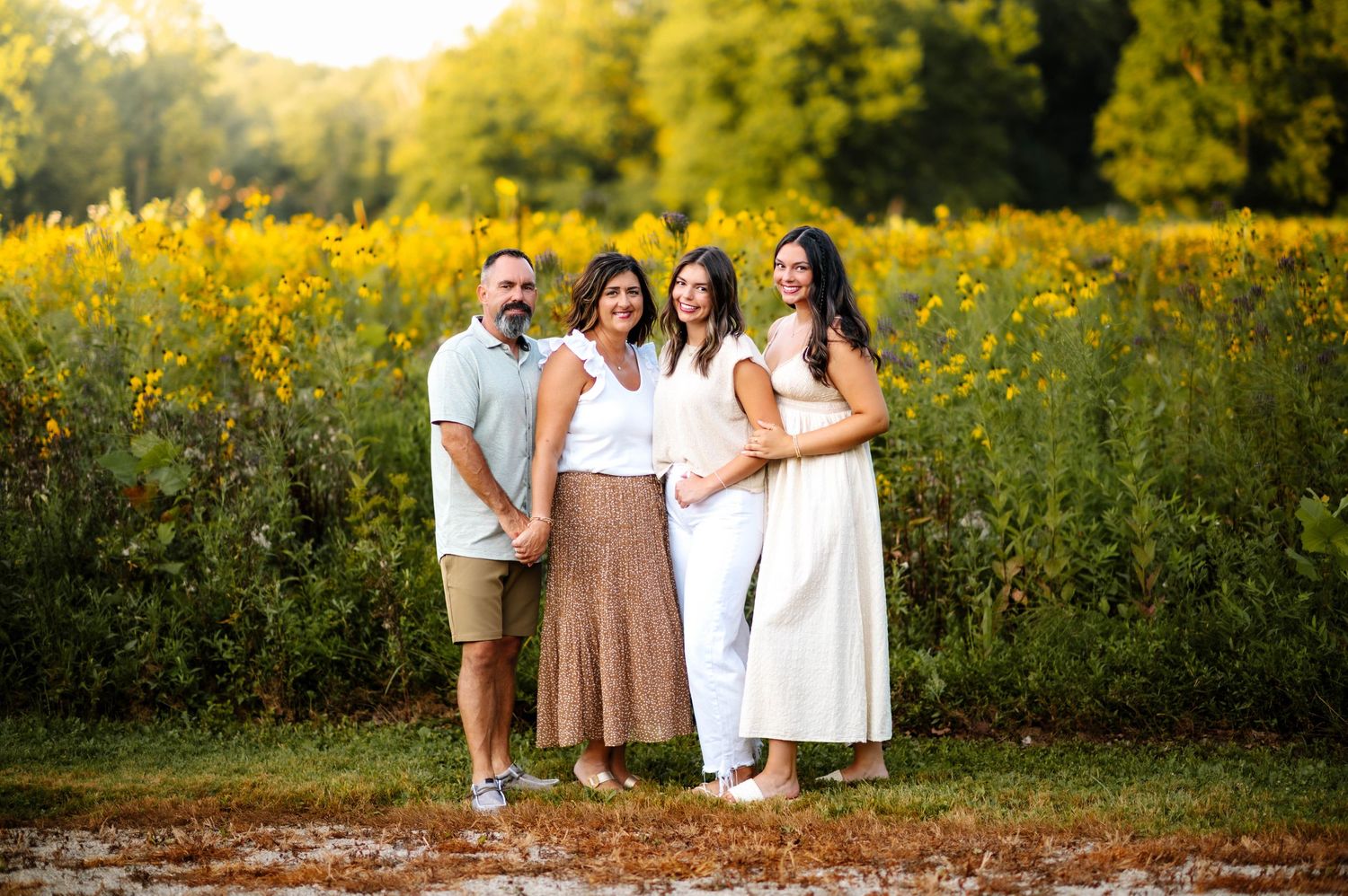 Candid family photo session in a blooming yellow flower field at sunset.