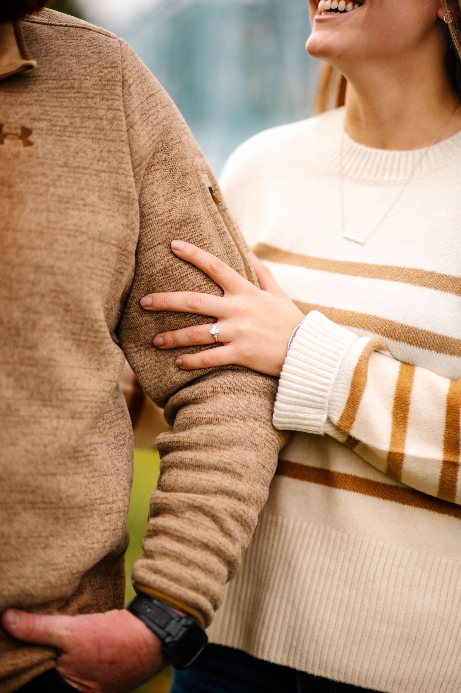 Close-up of couple wearing cozy sweaters during autumn engagement session.