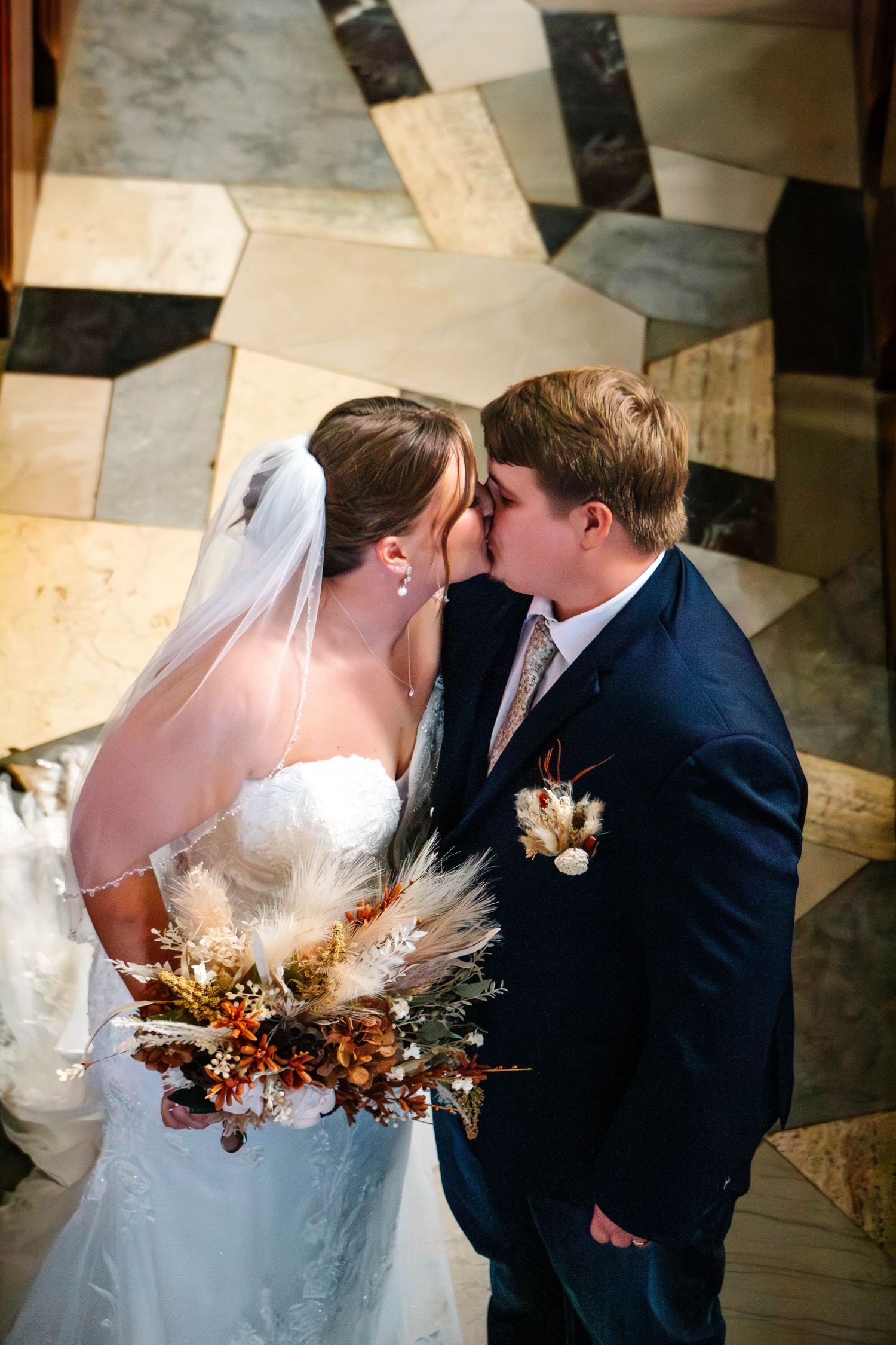 Wedding couple shares intimate moment with dried flower bouquet on checkered floor.