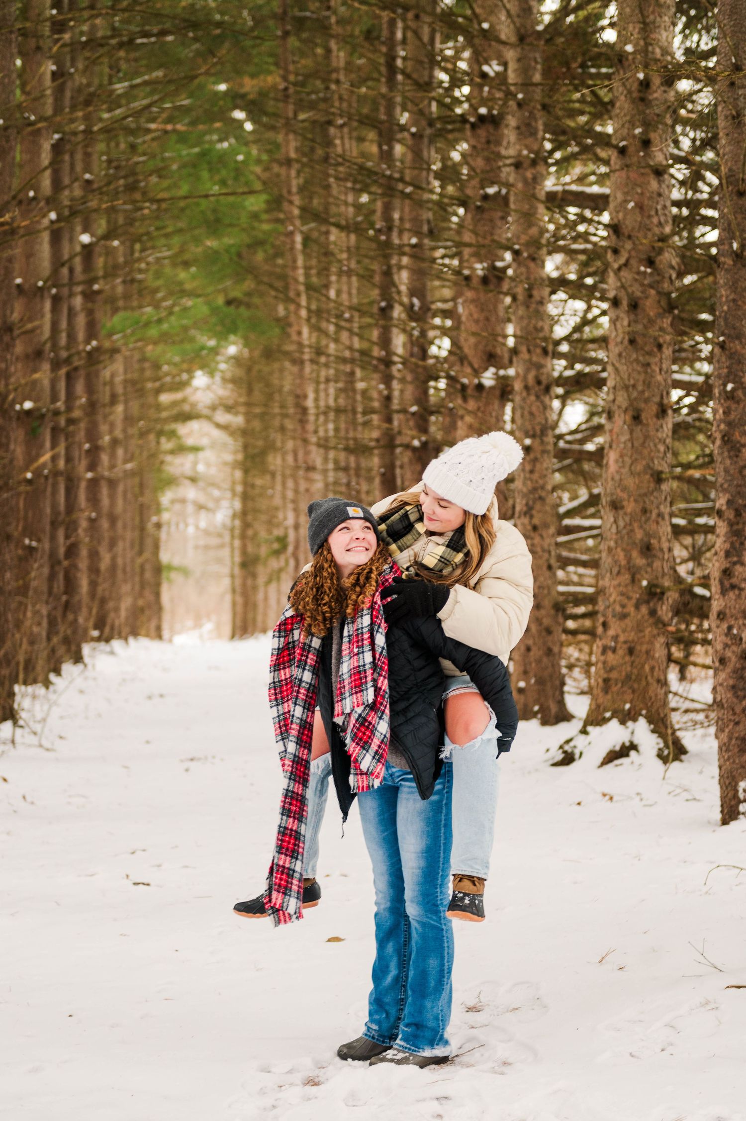 Two friends share a playful moment while enjoying the winter scenery in a pine forest.