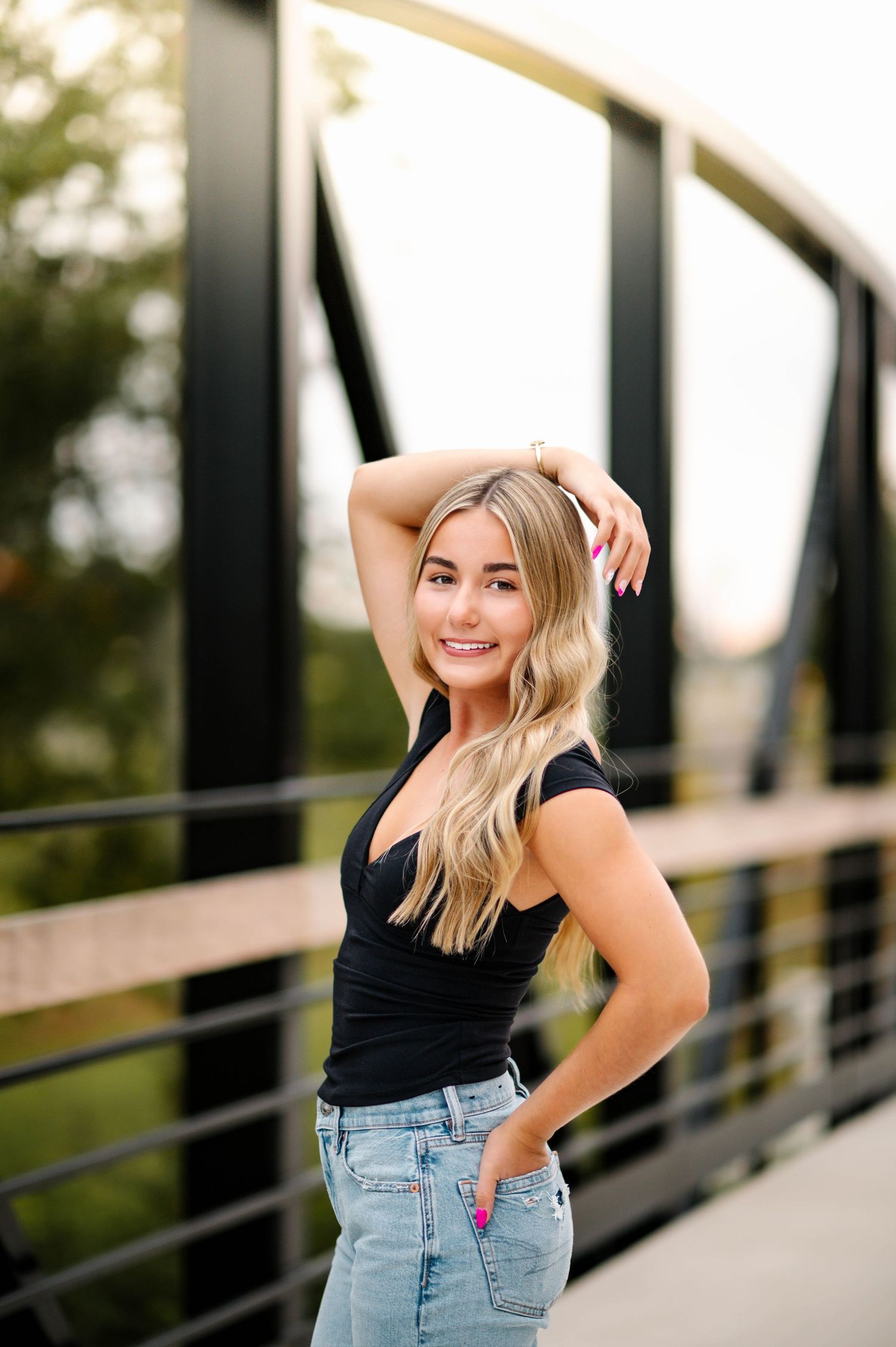 Candid poses against industrial bridge backdrop during golden hour photoshoot.