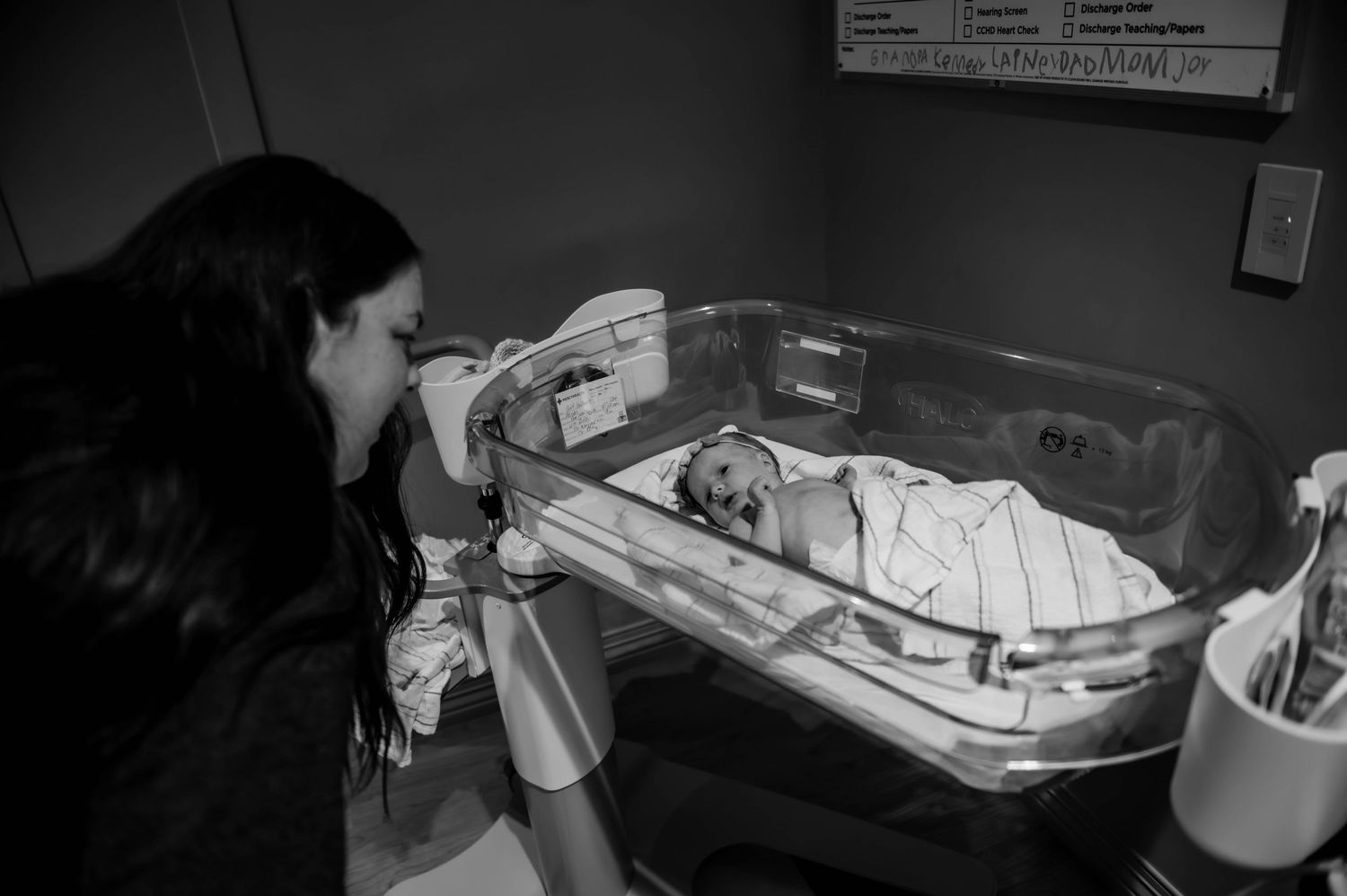 Hospital monitoring equipment surrounds a newborn baby in a medical bassinet.